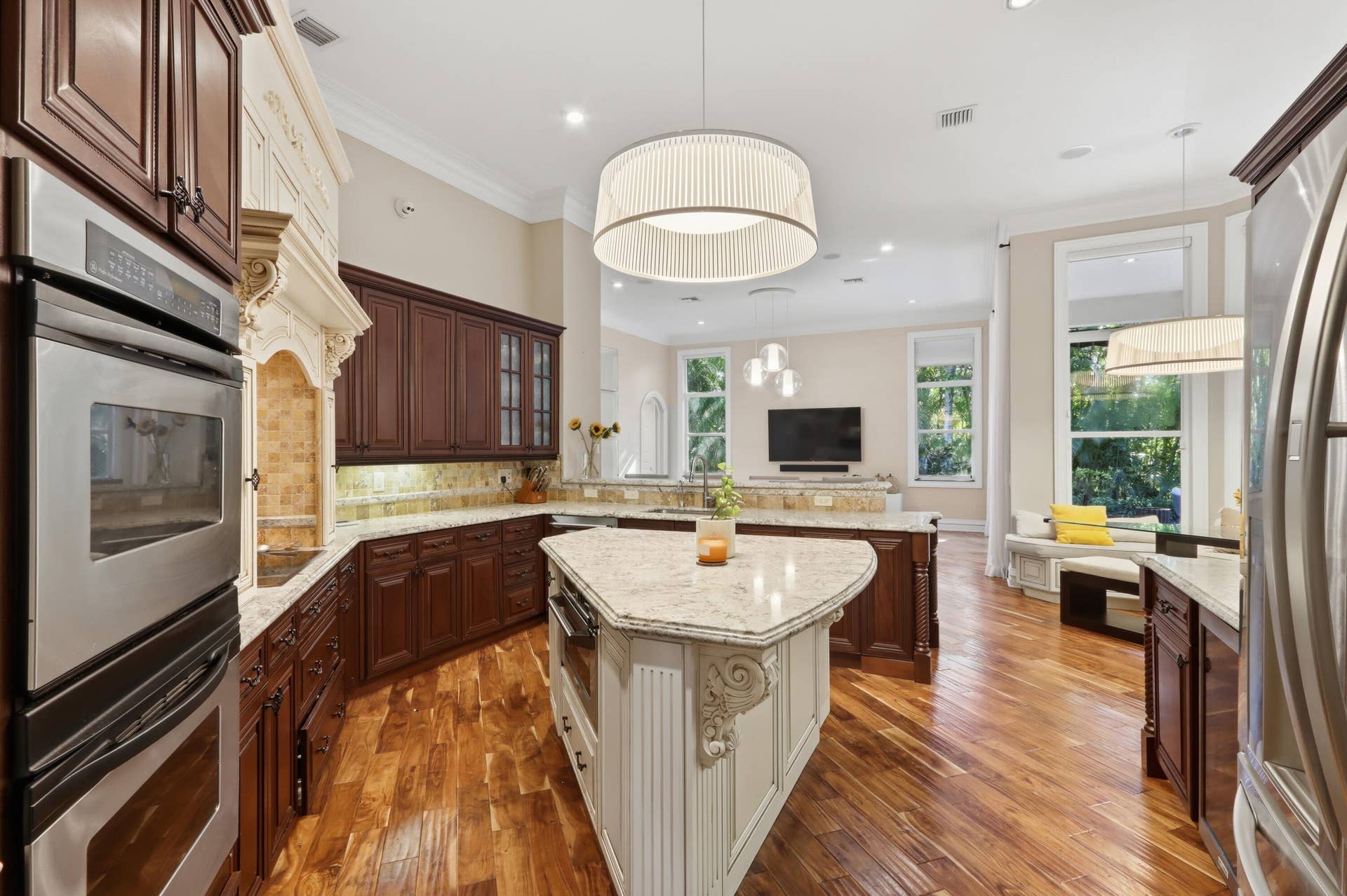 1580 VICTORIA ISLE Way, Weston, FL 33327 Kitchen featuring wood-finish flooring, stone countertops, custom cabinetry, stainless steel double wall ovens, and an expansive center island