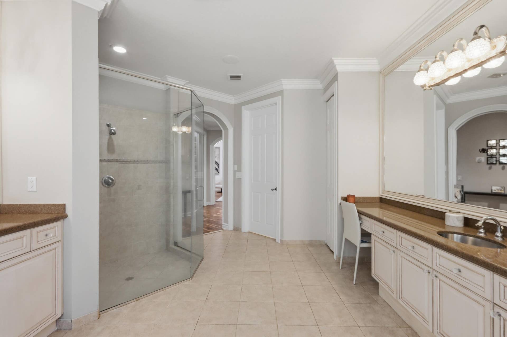 1580 VICTORIA ISLE Way, Weston, FL 33327 Glass-enclosed corner shower with neutral tile surround, extensive built-in cabinetry with stone-finish countertops, ceramic tile flooring, crown molding, and an oversized wall-mounted mirror