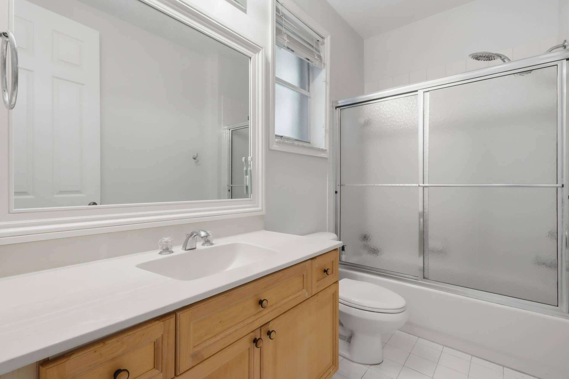 1580 VICTORIA ISLE Way, Weston, FL 33327 Bathroom featuring a wood-finish vanity with a rectangular sink, oversized wall-mounted mirror, white tile flooring, and a tub-shower combination with sliding glass doors