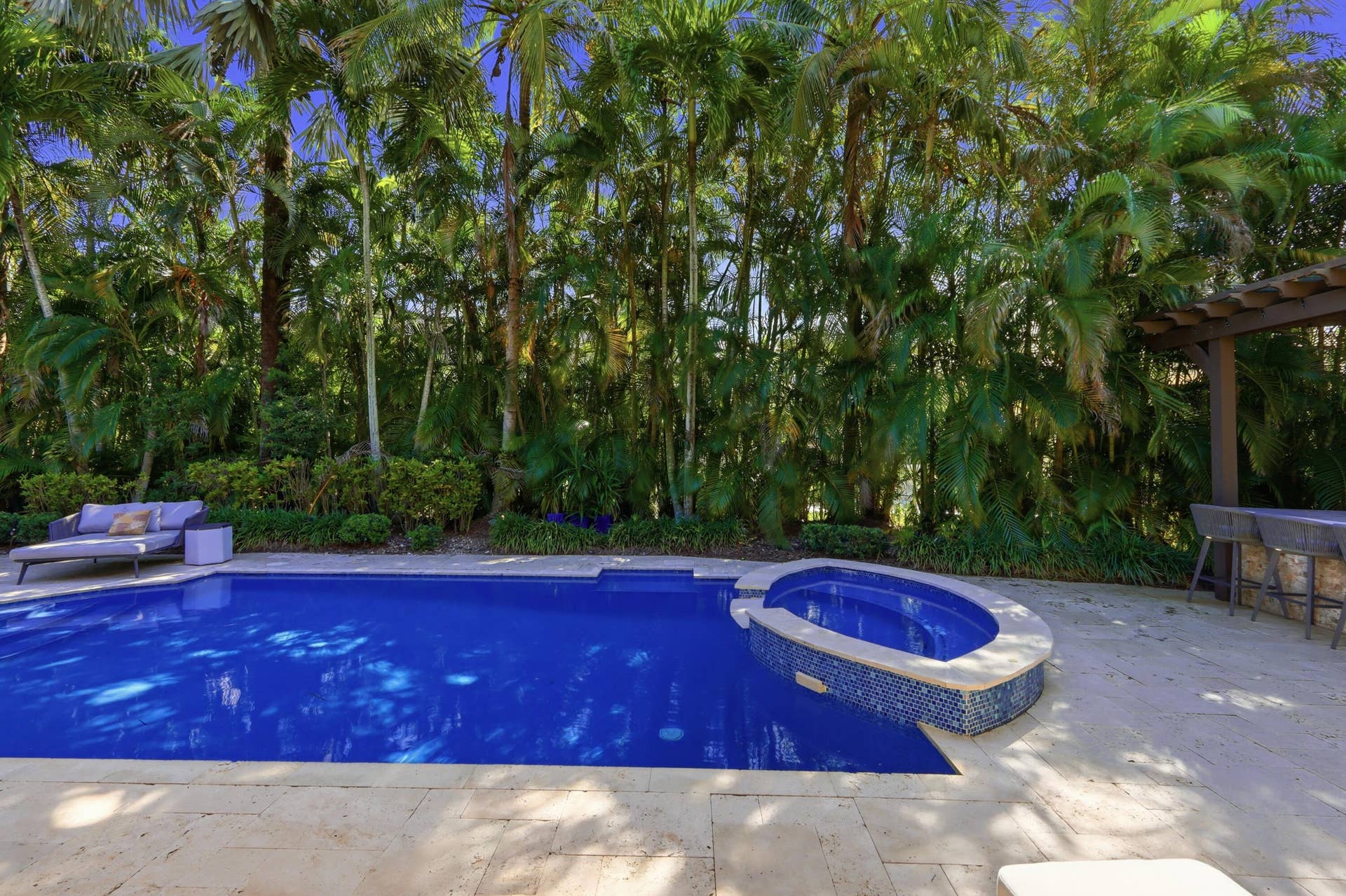 1580 VICTORIA ISLE Way, Weston, FL 33327 In-ground swimming pool with integrated elevated spa, stone pool decking, and wood-beam pergola