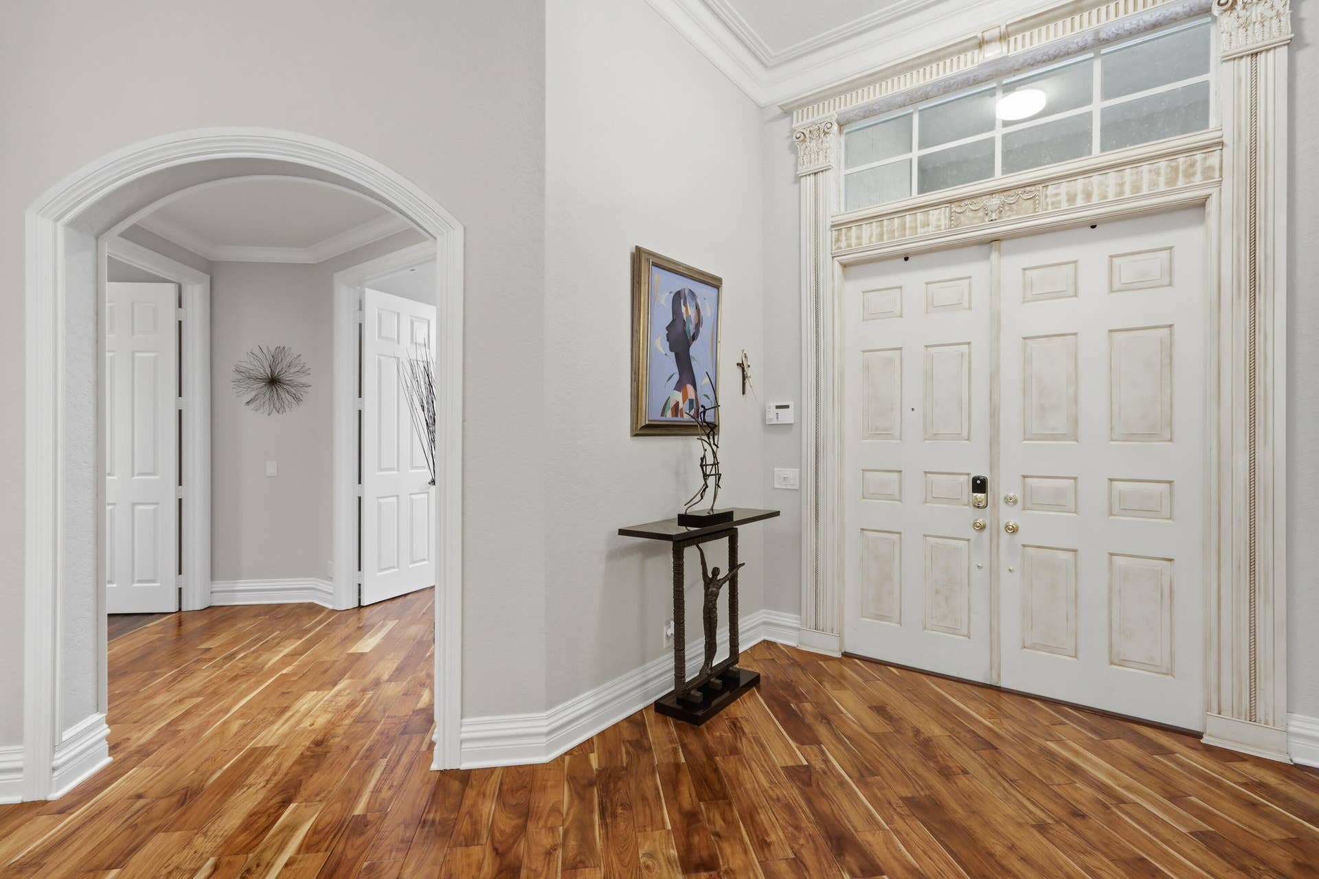 1580 VICTORIA ISLE Way, Weston, FL 33327 Entryway featuring dual paneled doors with decorative transom window, architectural crown molding, arched entryways, and wood-finish flooring
