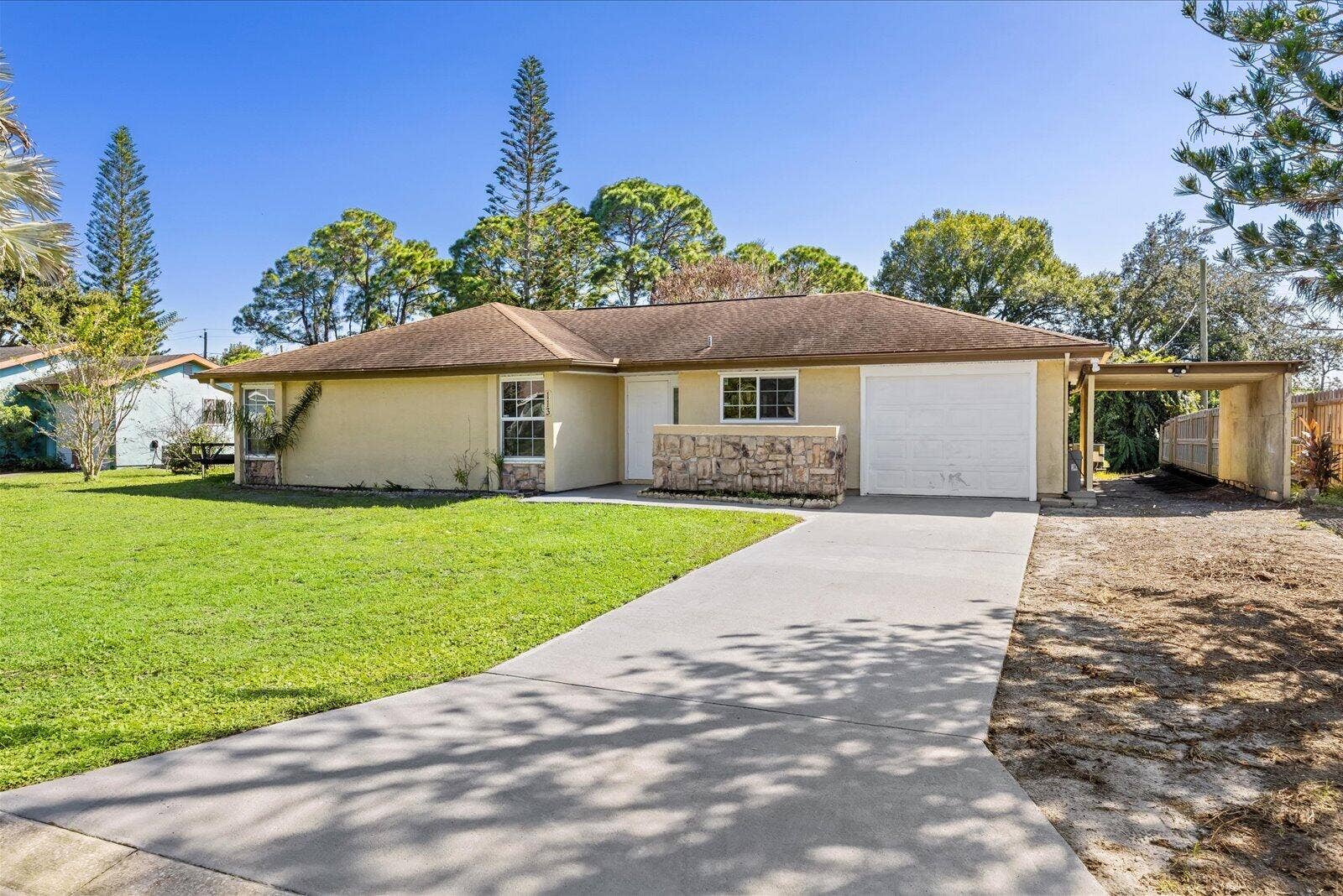 113 CONOVER Avenue, Sebastian, FL 32958 Single-story exterior featuring a stone-veneer accent wall, a concrete driveway, an attached garage, and a covered side carport