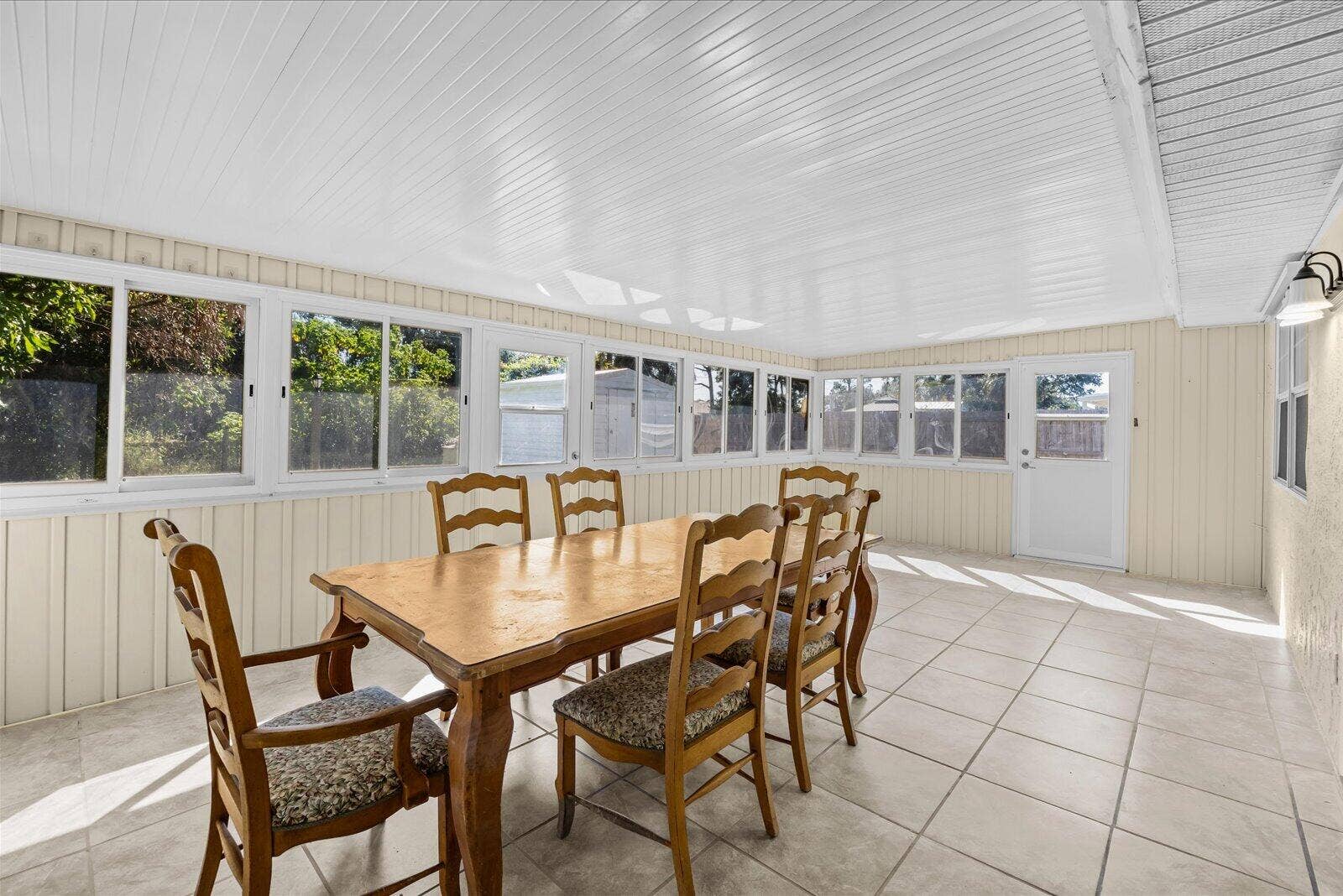 113 CONOVER Avenue, Sebastian, FL 32958 Enclosed sunroom featuring light-toned tile flooring, beadboard-style ceiling, extensive glass window pane wall, and a solid-panel exterior door with glass insert