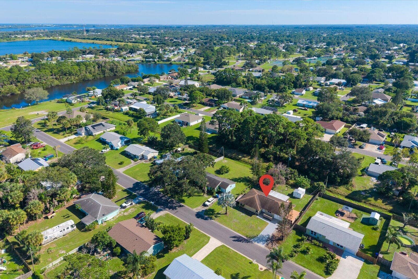 113 CONOVER Avenue, Sebastian, FL 32958 Aerial perspective of a residential property featuring a pitched roofline, paved driveway, expansive lawn, and mature canopy trees