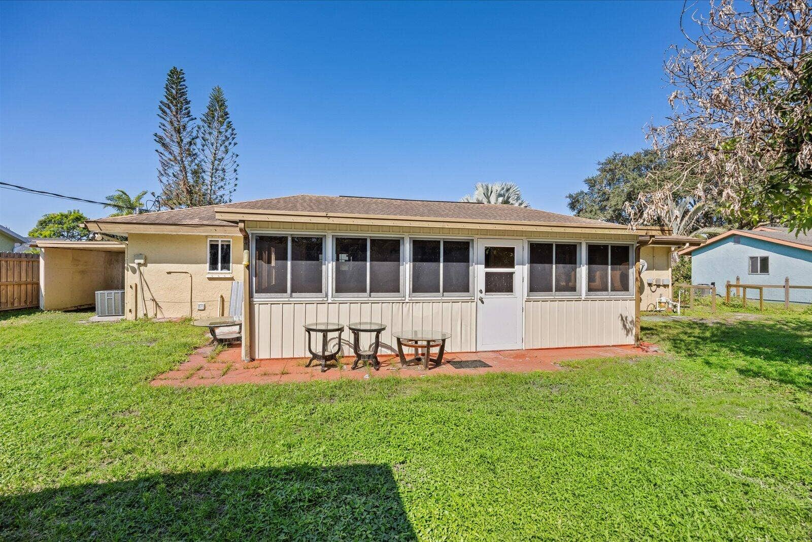 113 CONOVER Avenue, Sebastian, FL 32958 Enclosed rear porch featuring screen panels and a solid entry door, situated on a grass-covered lot with a paved patio