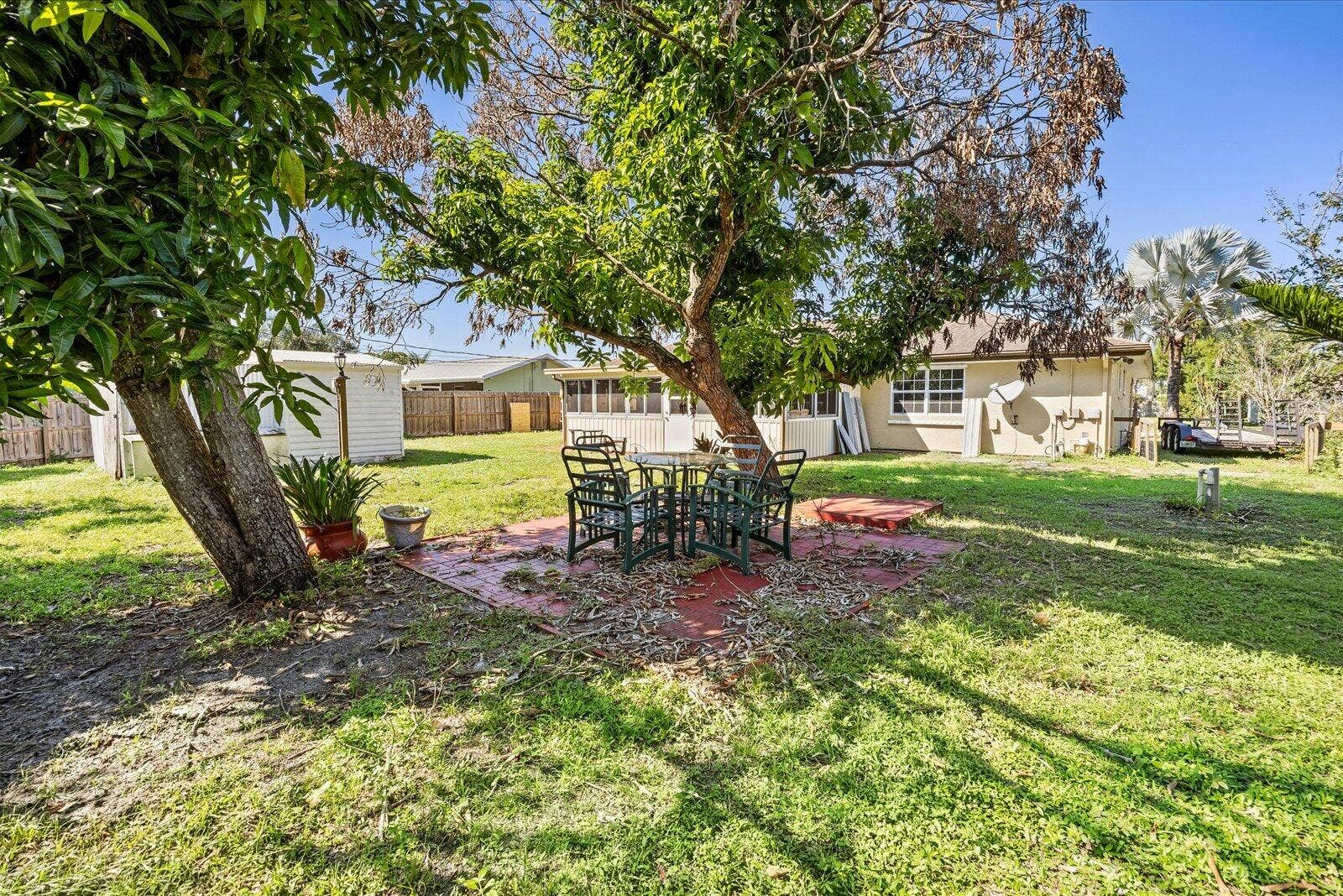 113 CONOVER Avenue, Sebastian, FL 32958 Spacious backyard featuring a dedicated paved patio area, mature shade trees, and a detached storage structure enclosed by wood perimeter fencing