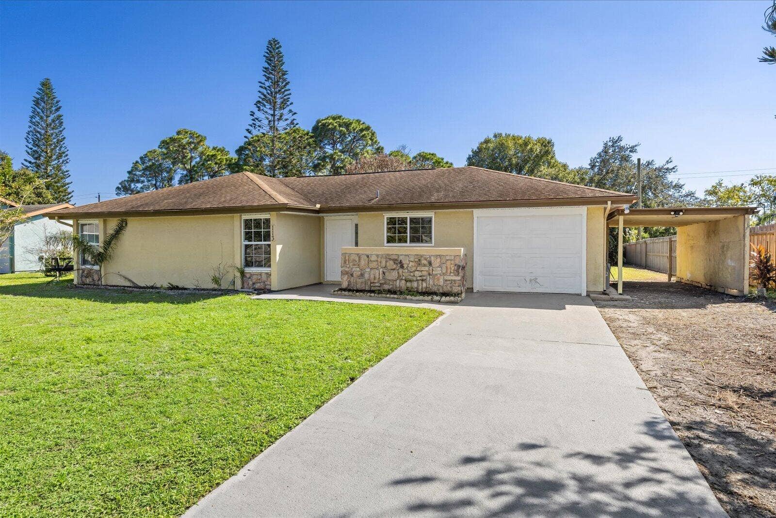 113 CONOVER Avenue, Sebastian, FL 32958 Single-story residence featuring a stone-clad facade, attached one-car garage, covered carport, and concrete driveway
