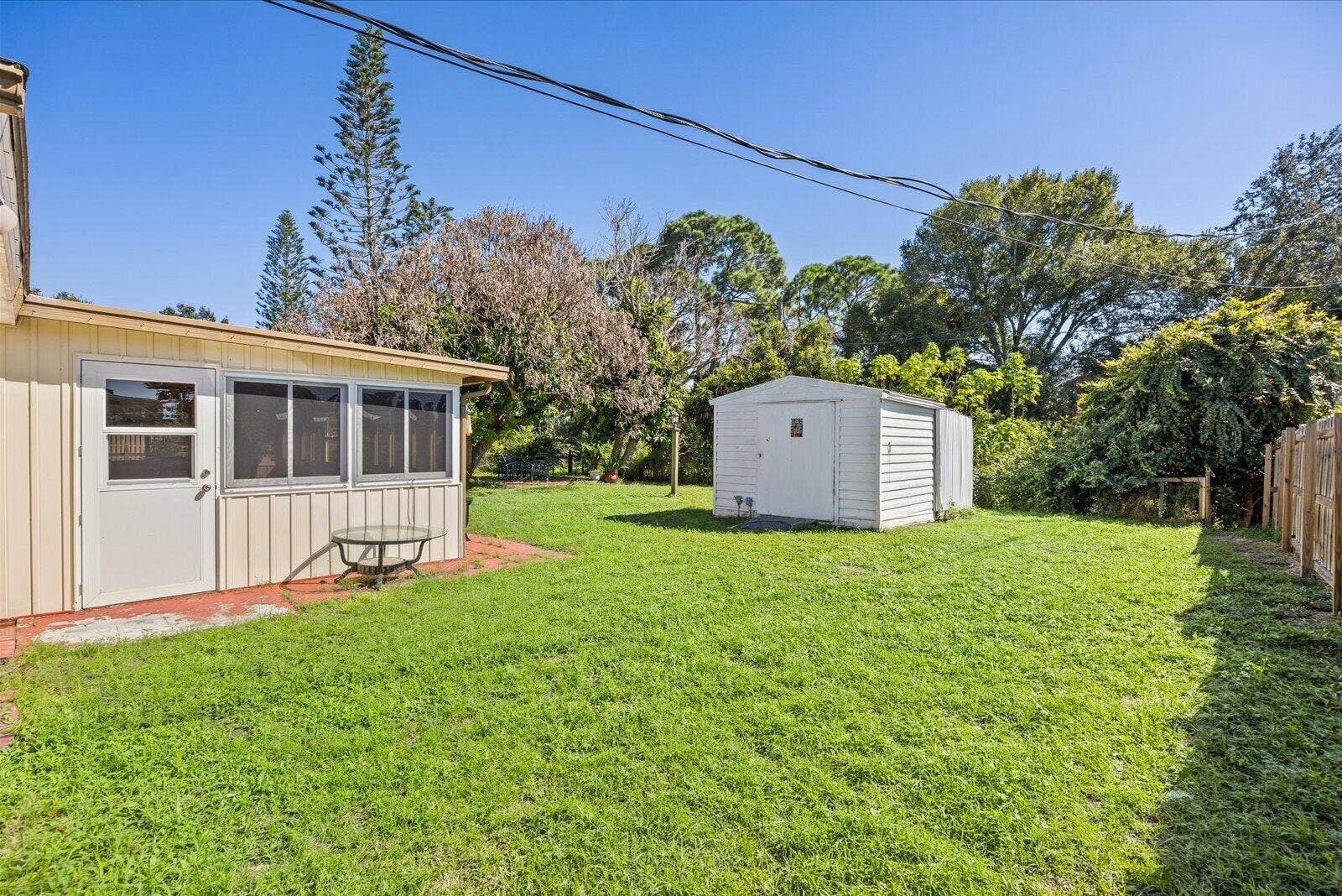 113 CONOVER Avenue, Sebastian, FL 32958 Expansive backyard featuring a level lawn, mature trees, a detached storage shed, and vertical panel siding exterior