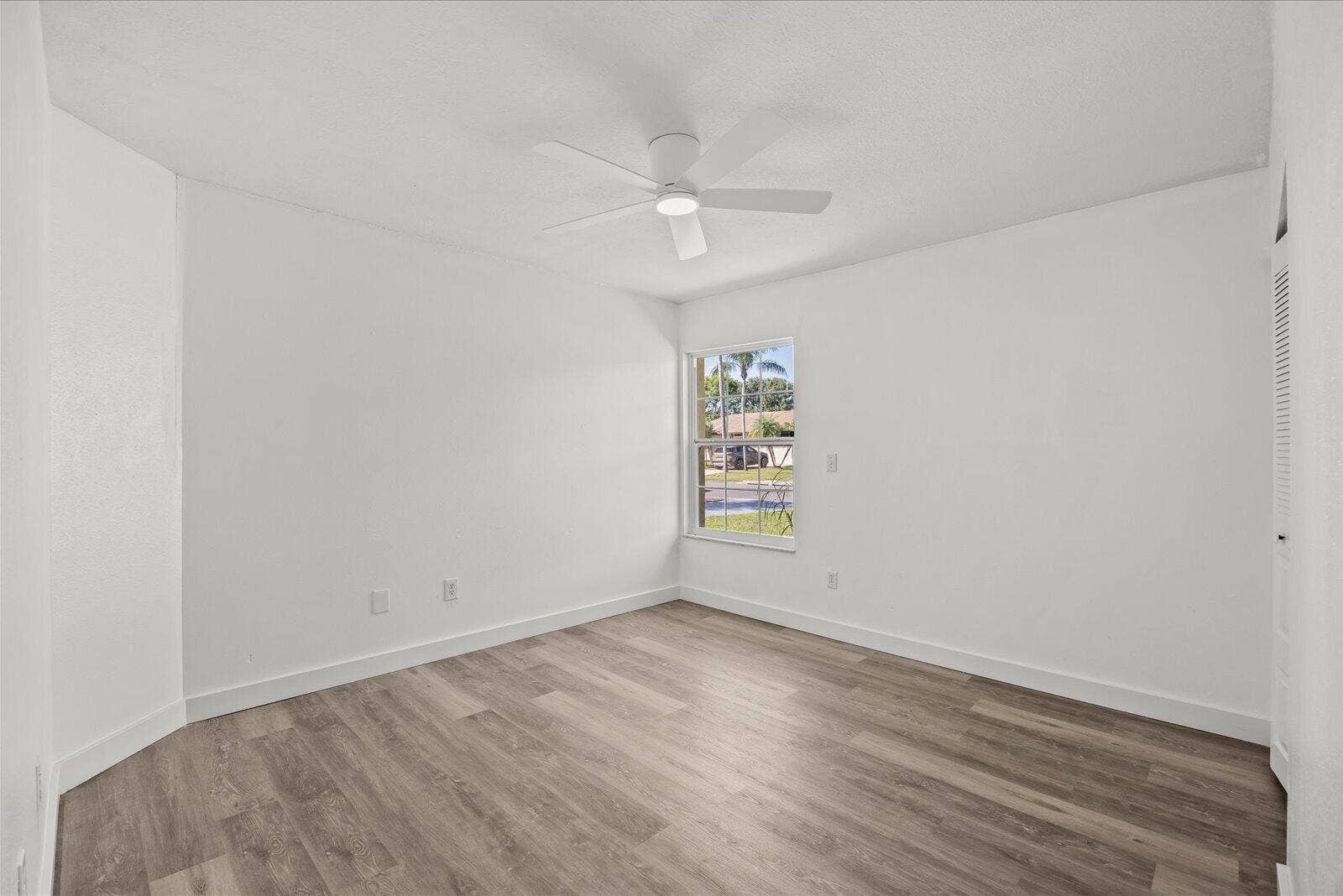 113 CONOVER Avenue, Sebastian, FL 32958 Interior room featuring wood-finish flooring, a neutral white color palette, a single-pane window, a ceiling-mounted light fixture, and a louvered closet door
