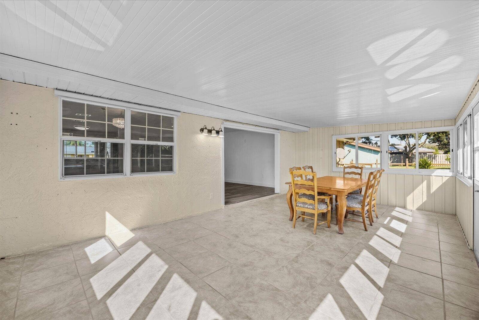 113 CONOVER Avenue, Sebastian, FL 32958 Enclosed patio featuring large-format tile flooring, a tongue-and-groove ceiling, multi-pane windows, and wall-mounted light fixtures