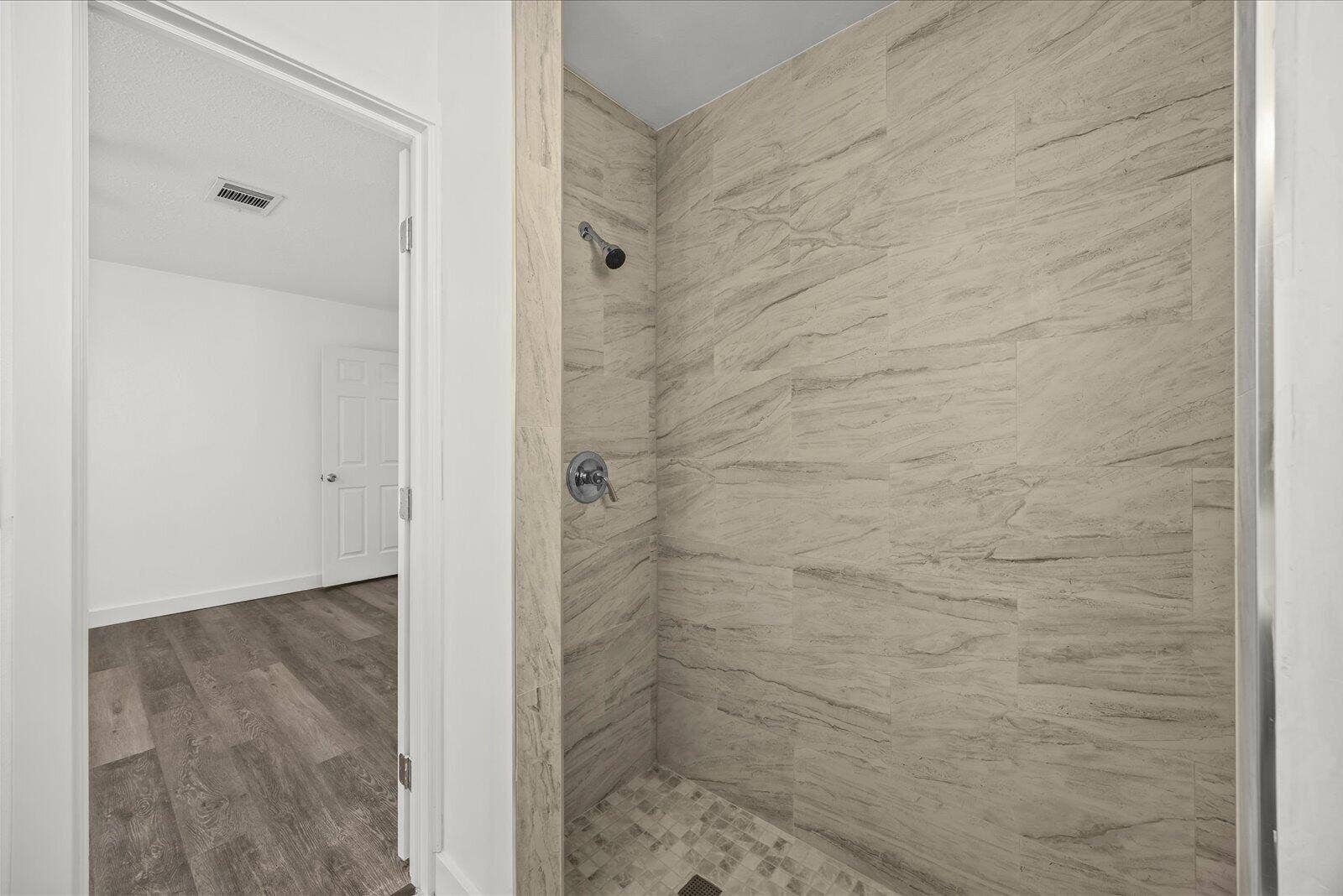 113 CONOVER Avenue, Sebastian, FL 32958 Walk-in shower featuring floor-to-ceiling stone-patterned tile, stone-tiled flooring, and a metallic shower fixture