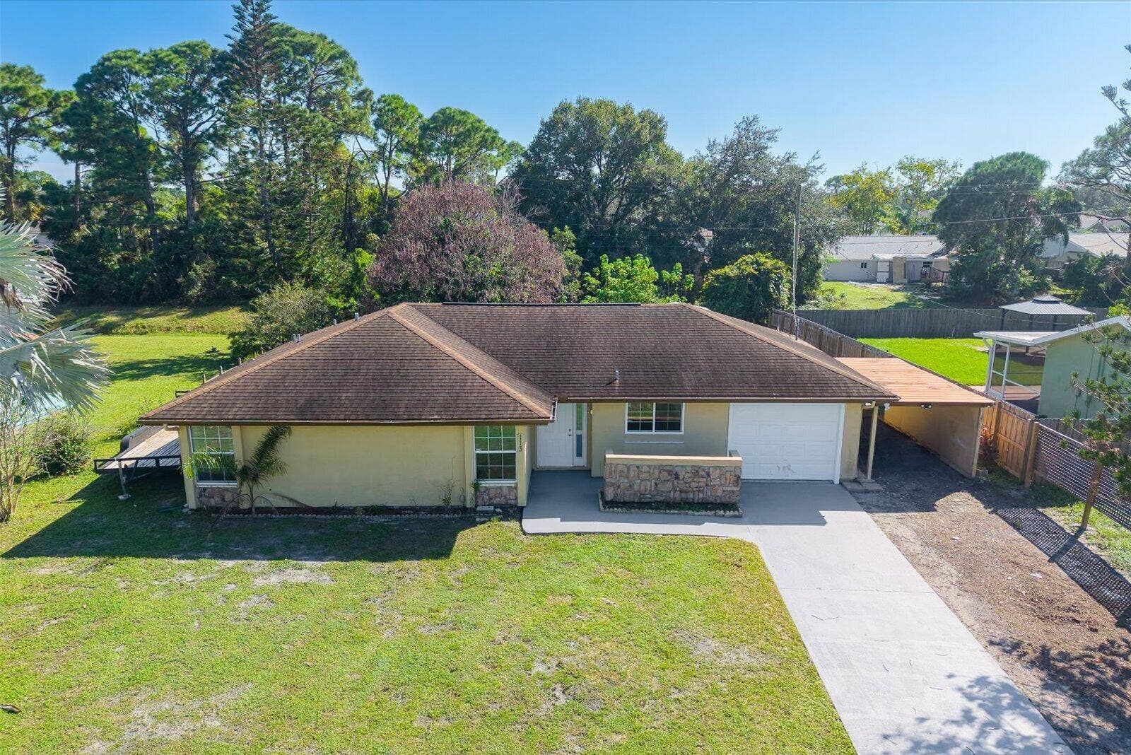 113 CONOVER Avenue, Sebastian, FL 32958 Single-story residence featuring a hipped roof, stone-veneer exterior accents, attached garage, and a covered side carport