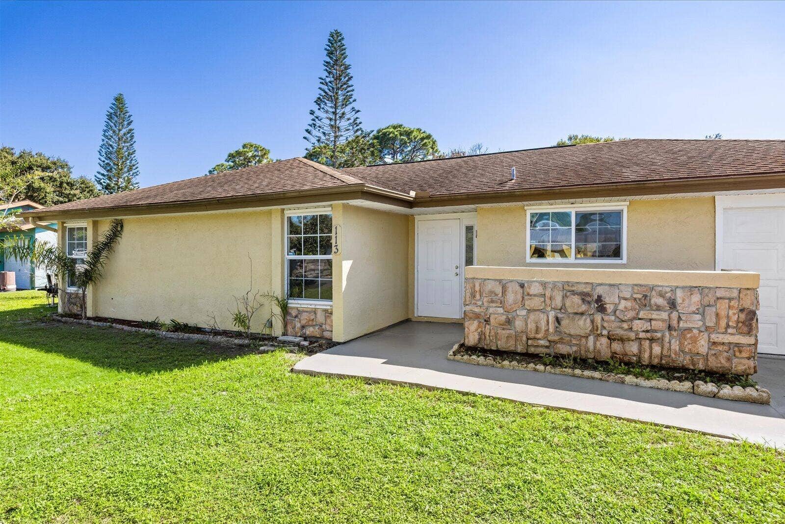 113 CONOVER Avenue, Sebastian, FL 32958 Single-story exterior featuring light-toned stucco, a multi-paneled front door, stone masonry facade detail, and a concrete walkway