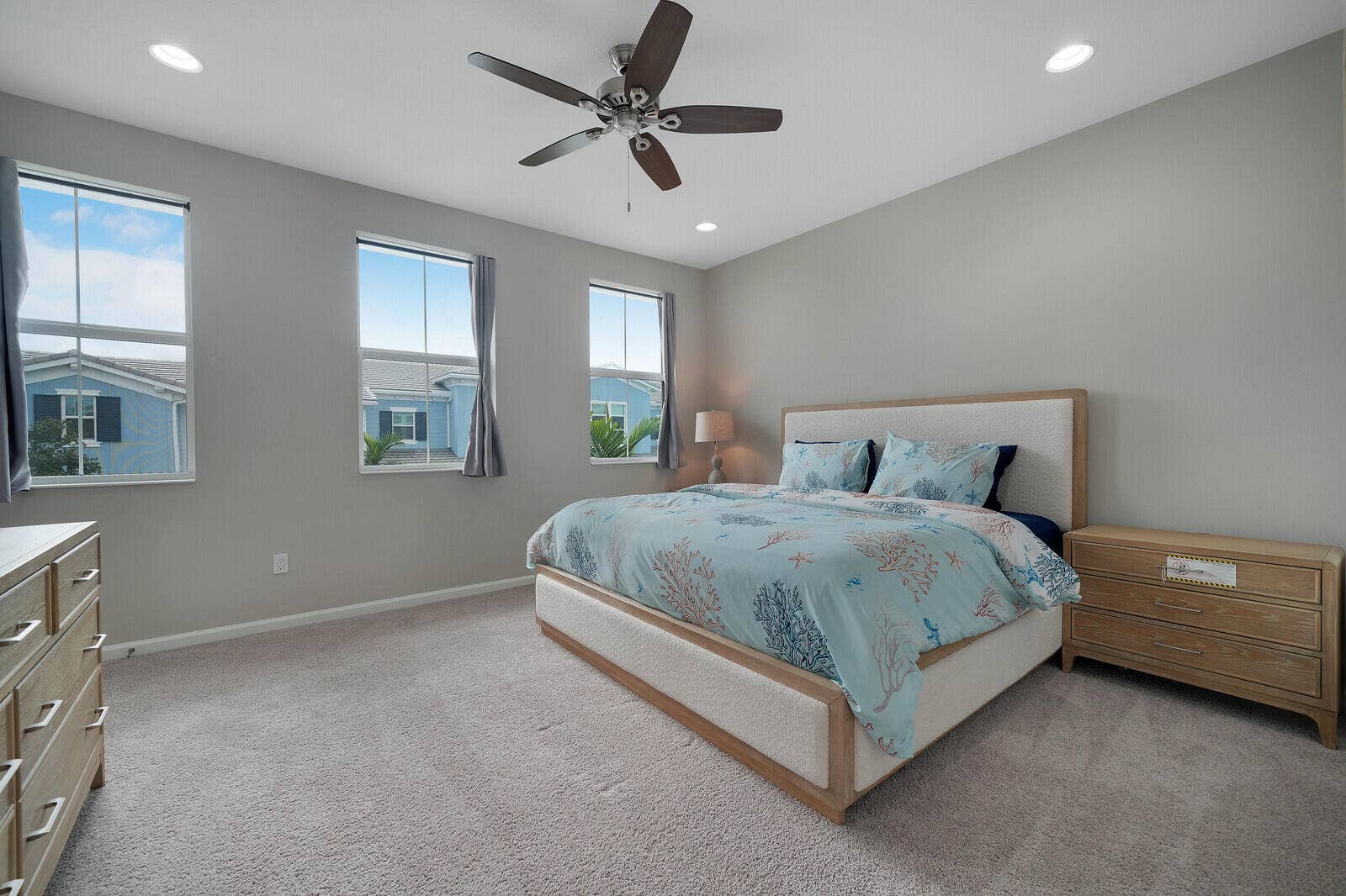 Neutral-toned interior featuring recessed lighting, a multi-blade ceiling fan, and three windows with dual-pane frames