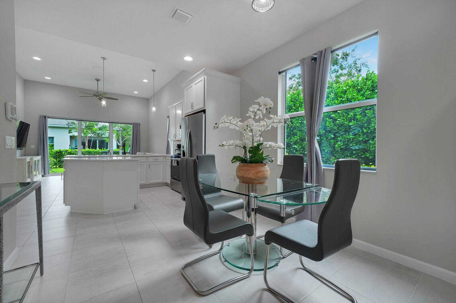 Open-concept kitchen featuring white cabinetry, a center island with countertop seating, large-format tile flooring, and recessed lighting