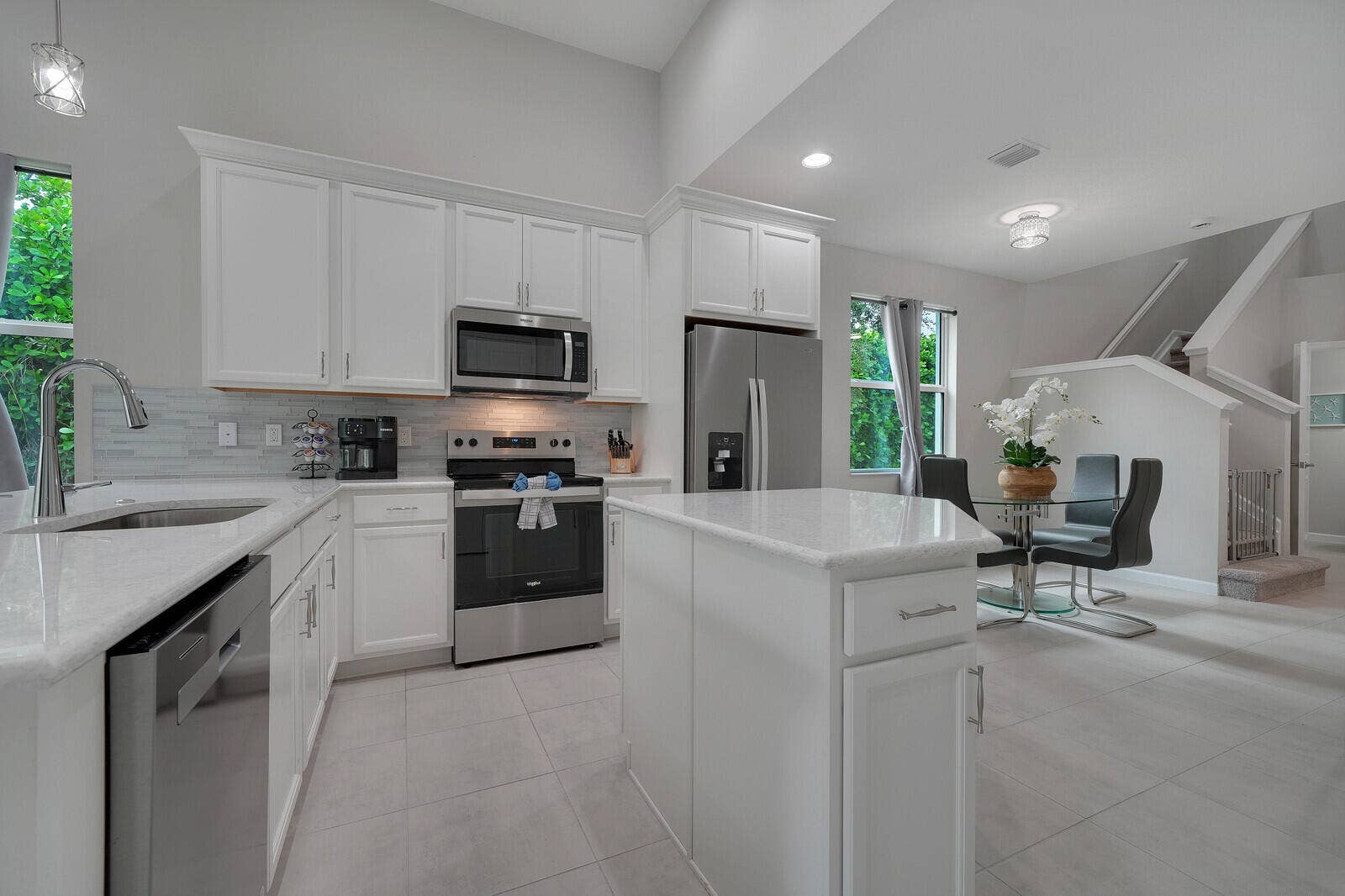 Kitchen featuring white shaker cabinetry, granite countertops, a central island, stainless steel appliances and tile flooring