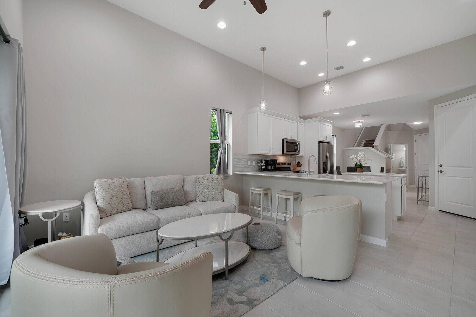 High ceilings, tile flooring, recessed lighting, white cabinetry, and a breakfast bar
