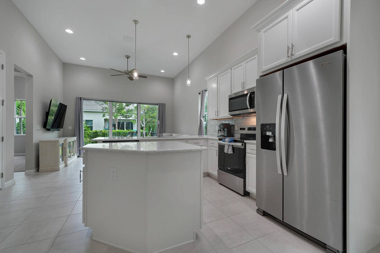Kitchen featuring white cabinetry, extended countertops perfect for functional living/cooking and entertaining, stainless steel appliances, a center island, and vaulted ceilings