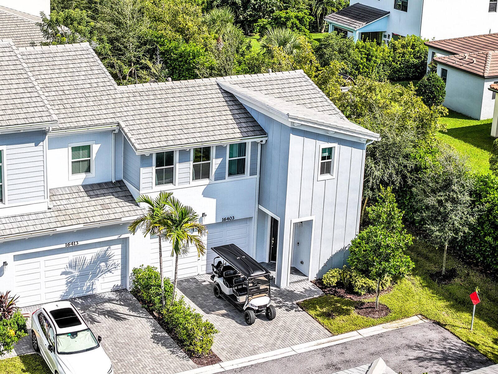 Multi-story exterior featuring board-and-batten siding, tile roofing, and a paved driveway with a two-car garage