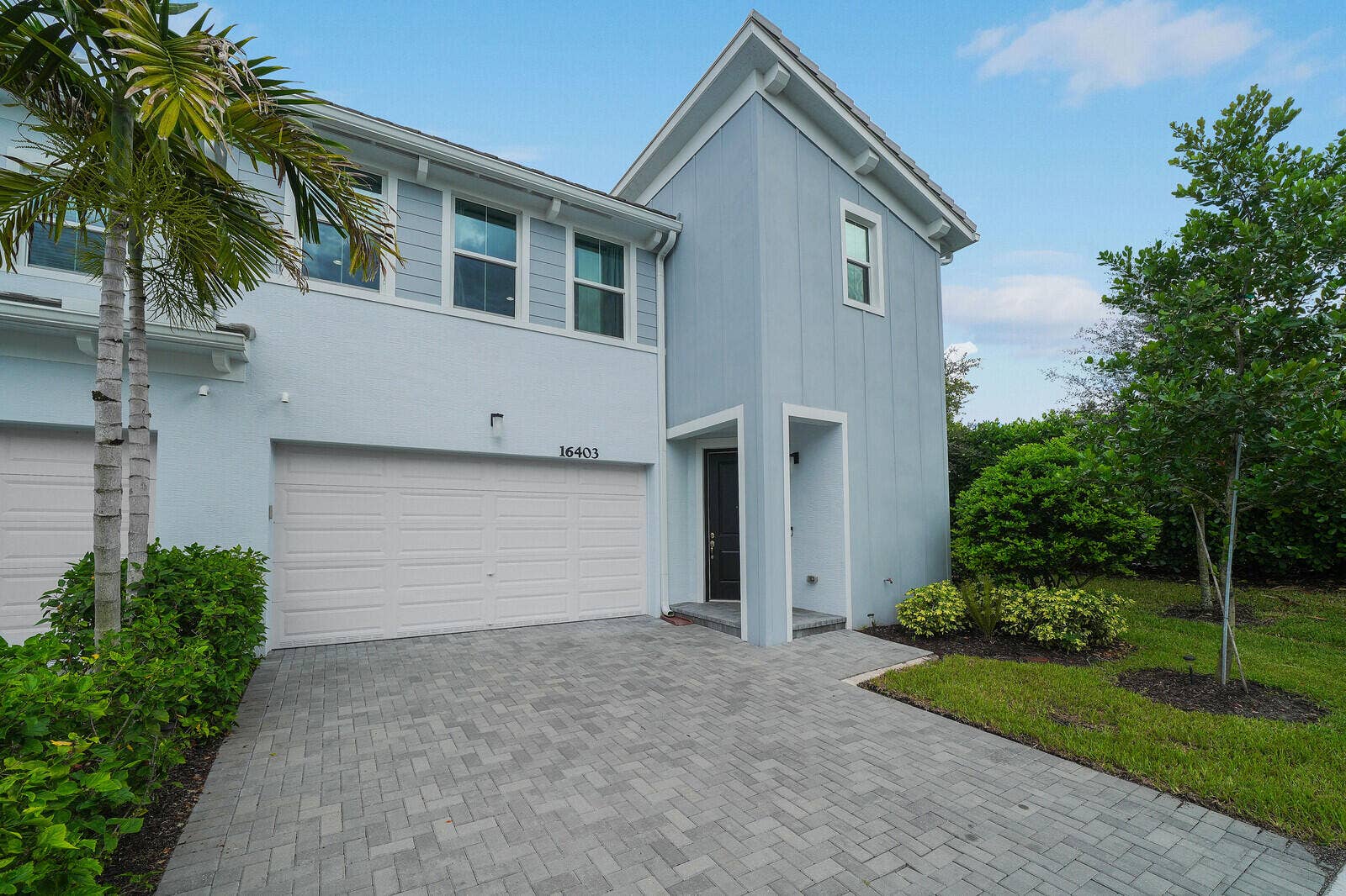 Two-story, End Unit, Bay Collection Adventura Model, Urban Transitional exterior featuring board-and-batten siding, a paved driveway, a two-car garage, and an inset covered entryway on a dead end street.