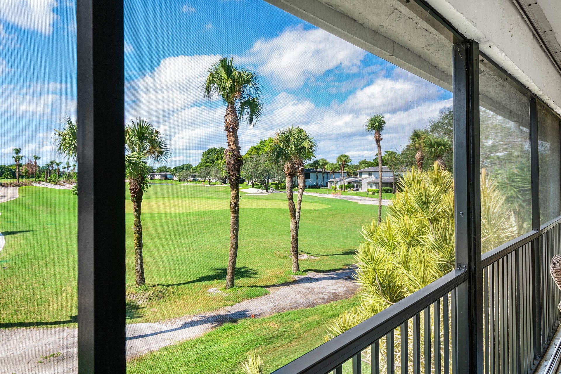21 Southport Lane, #B, Boynton Beach, FL 33436 Screened-in balcony featuring a metal railing and expansive golf course landscape with mature palm trees