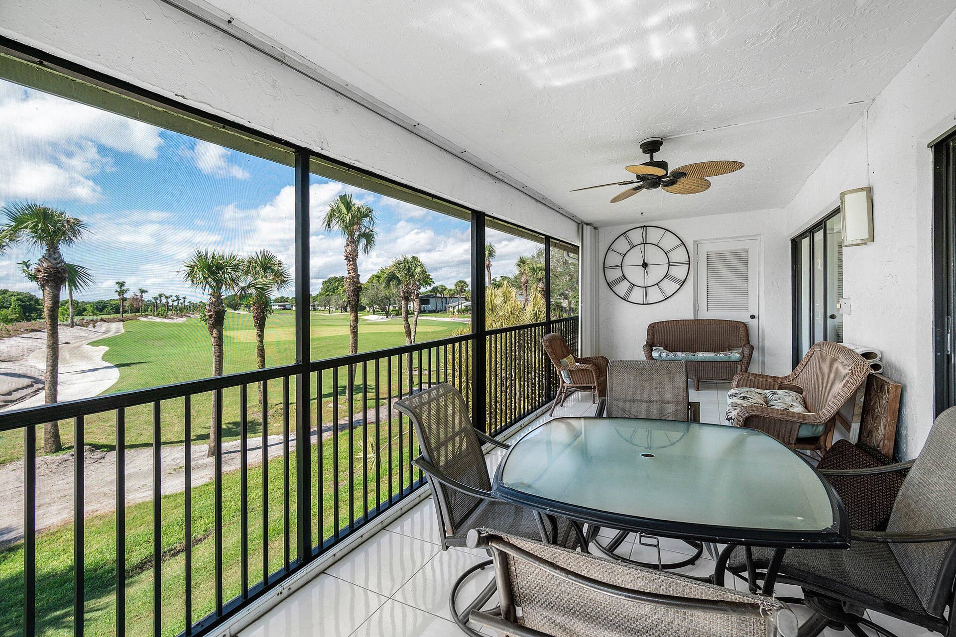 21 Southport Lane, #B, Boynton Beach, FL 33436 Screened-in balcony with tile flooring, black metal railing, and overhead ceiling fan, featuring an expansive outdoor perspective