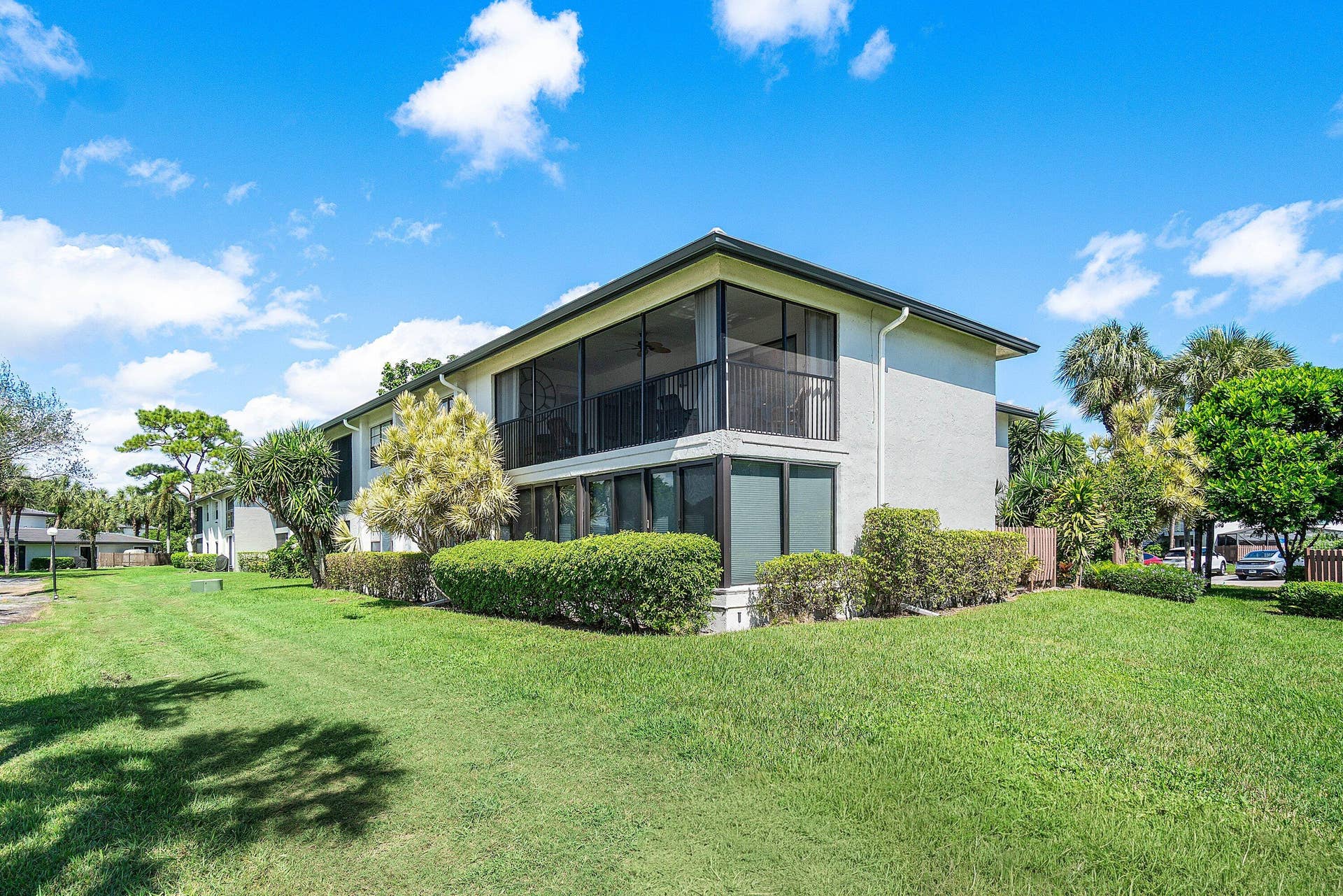 21 Southport Lane, #B, Boynton Beach, FL 33436 Multi-story exterior featuring light-toned masonry, tiered screened enclosures, and expansive surrounding green space