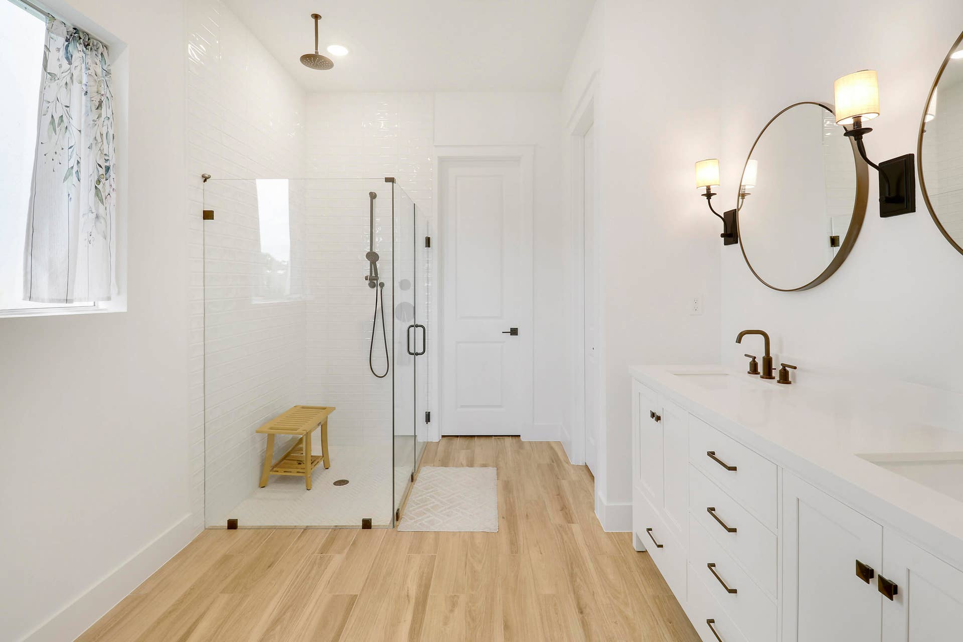 6742 SE LOST PINE Drive, Stuart, FL 34997 Double vanity with rectangular sinks, glass-enclosed walk-in shower featuring a rainfall showerhead, and wood like flooring