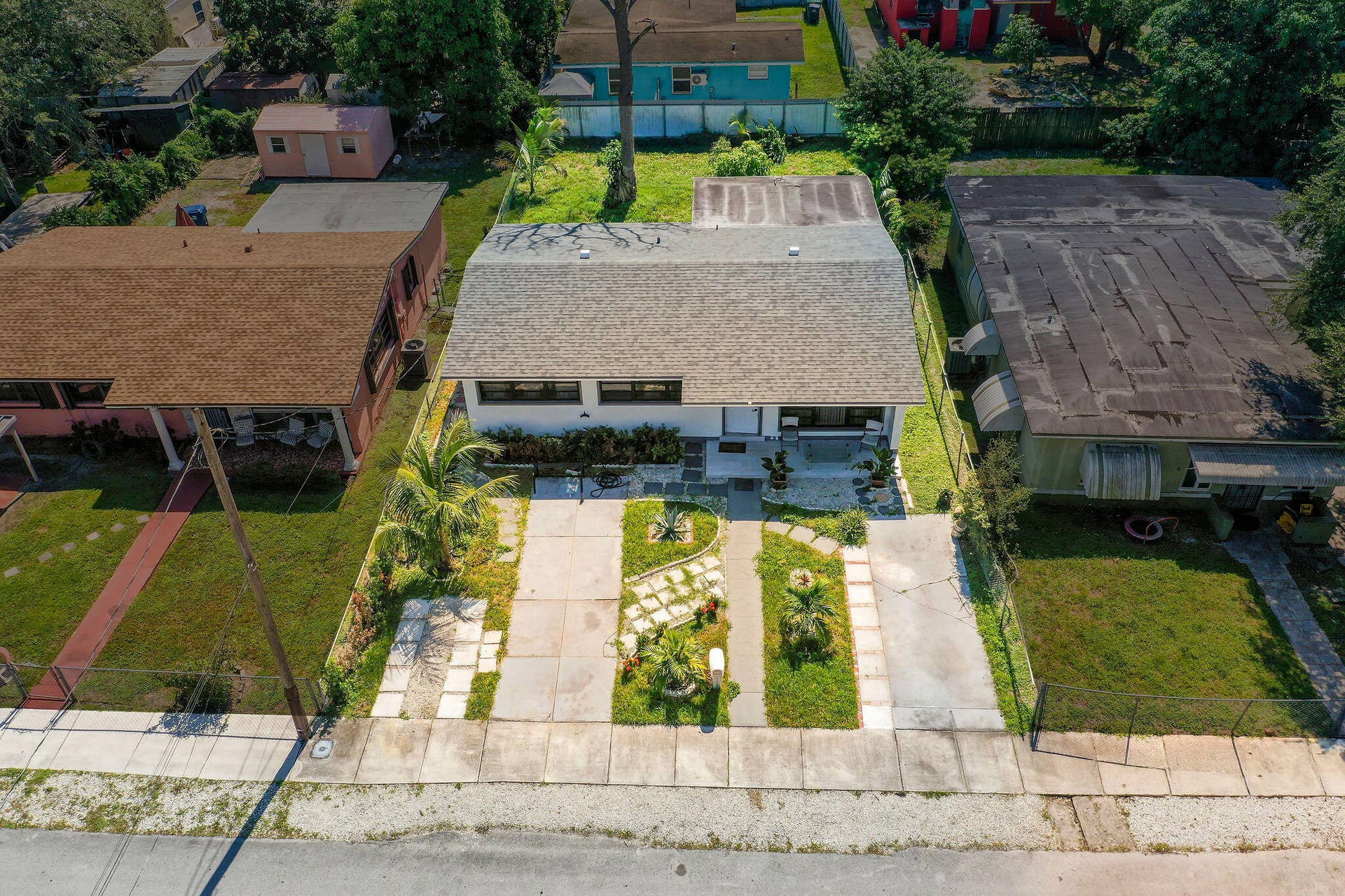 1946 NW 152nd Terrace, Miami Gardens, FL 33054 Exterior view of a single-story residence featuring a shingled gable roof, a concrete driveway, a segmented paver walkway, and landscaped front grounds