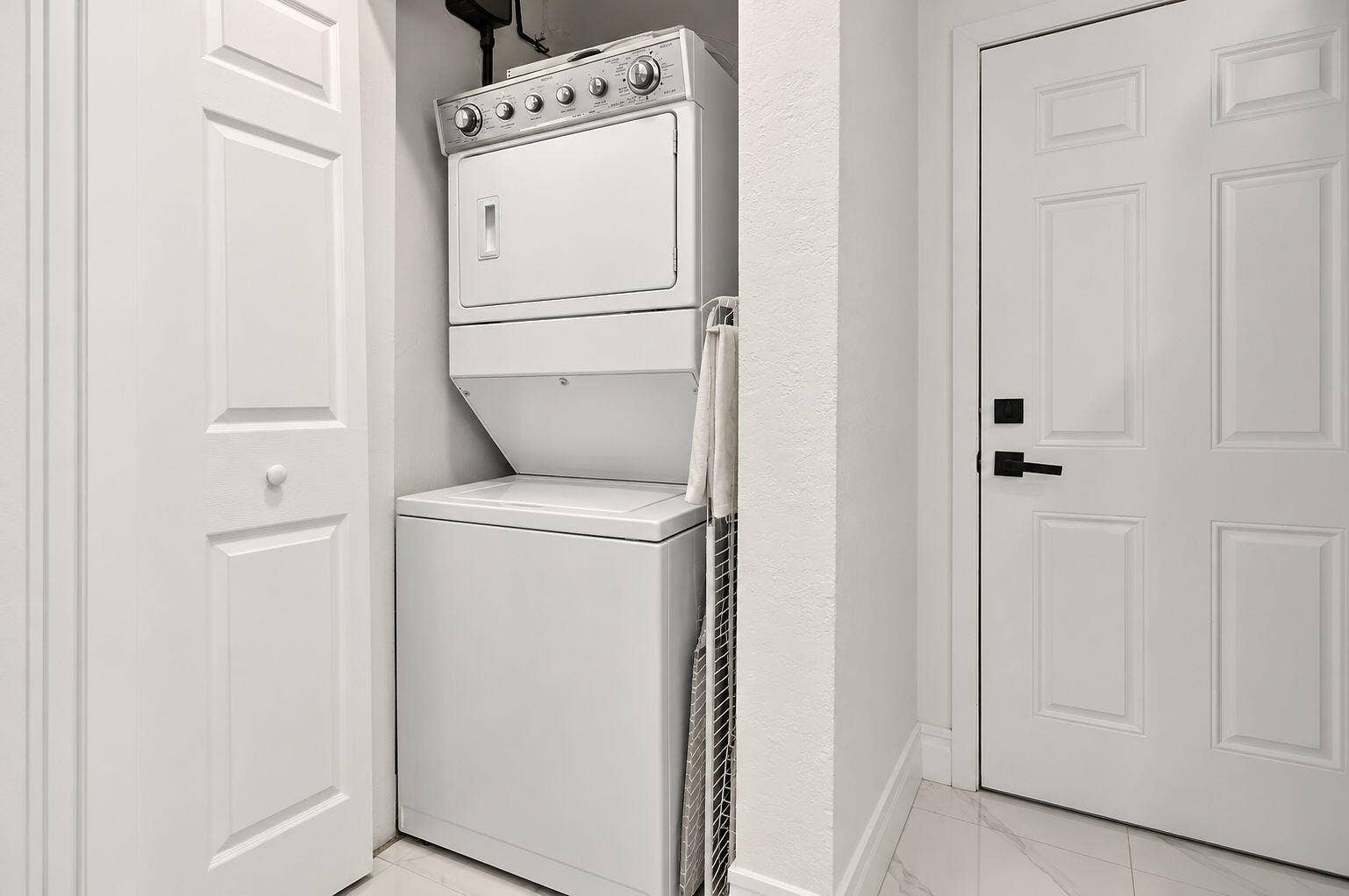 1946 NW 152nd Terrace, Miami Gardens, FL 33054 Laundry area featuring a stacked washer and dryer unit, four-panel interior doors, and tile flooring