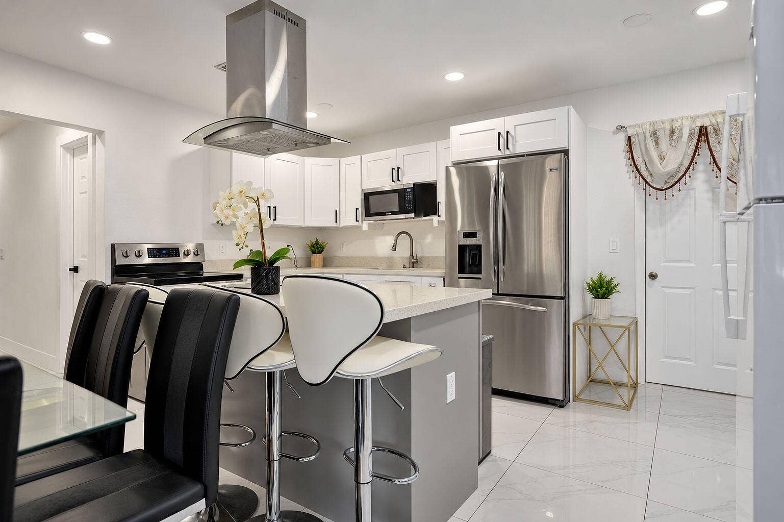 1946 NW 152nd Terrace, Miami Gardens, FL 33054 Kitchen featuring white shaker-style cabinetry, quartz countertops, stainless steel appliances, a stainless steel range hood, and tile flooring