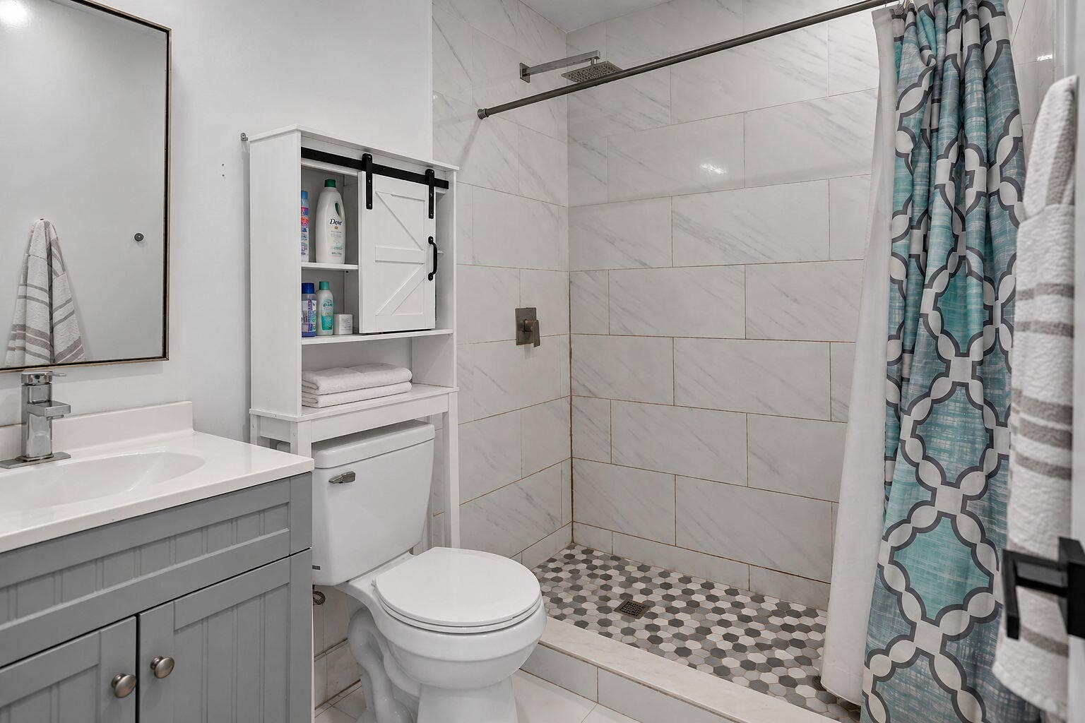 1946 NW 152nd Terrace, Miami Gardens, FL 33054 Grey shaker-style vanity with a solid surface countertop, rectangular under-mount sink, white subway-style shower wall tile, and geometric patterned shower floor tile