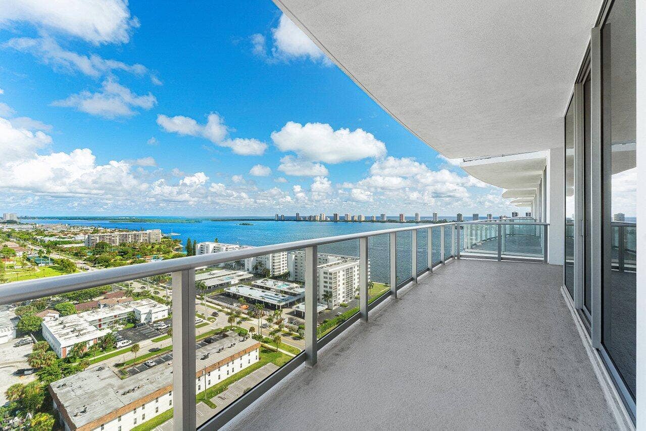 Expansive balcony featuring a metal-frame glass railing, concrete flooring, and sliding glass door access