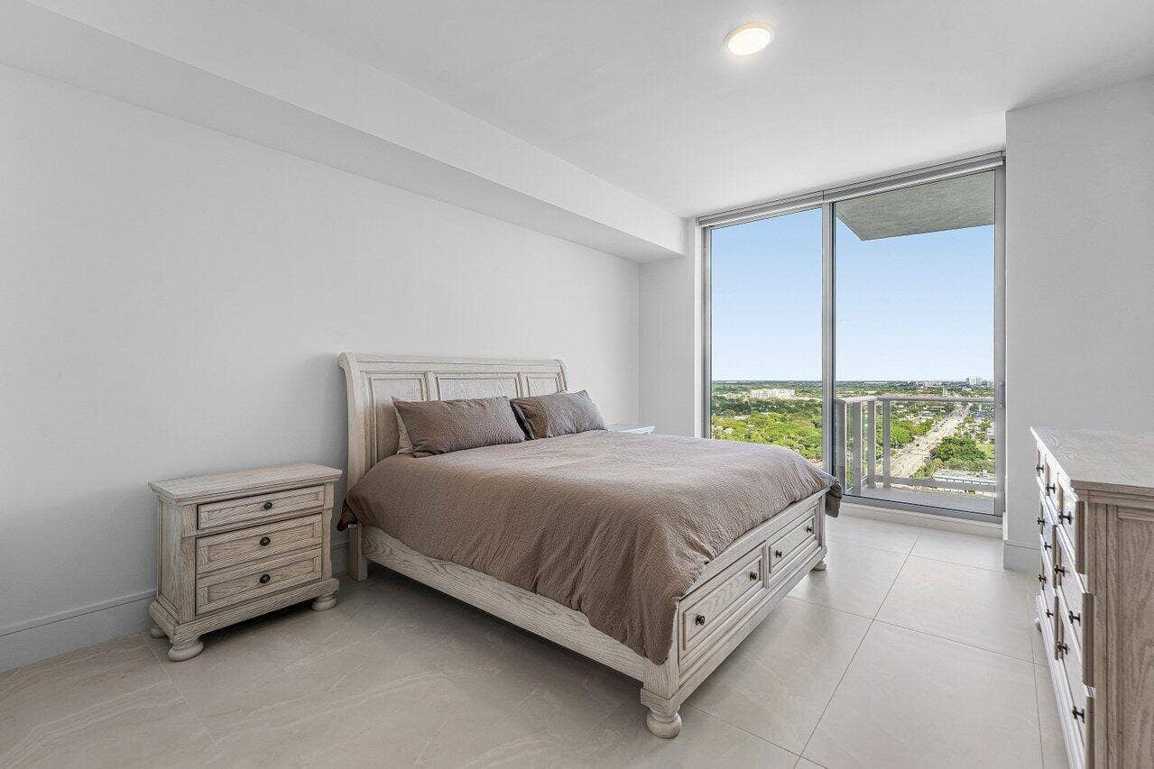 Floor-to-ceiling sliding glass doors, neutral tile flooring, and a private balcony