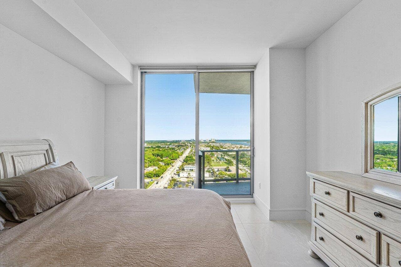 Floor-to-ceiling glass sliding door, balcony access, and light-toned tile flooring