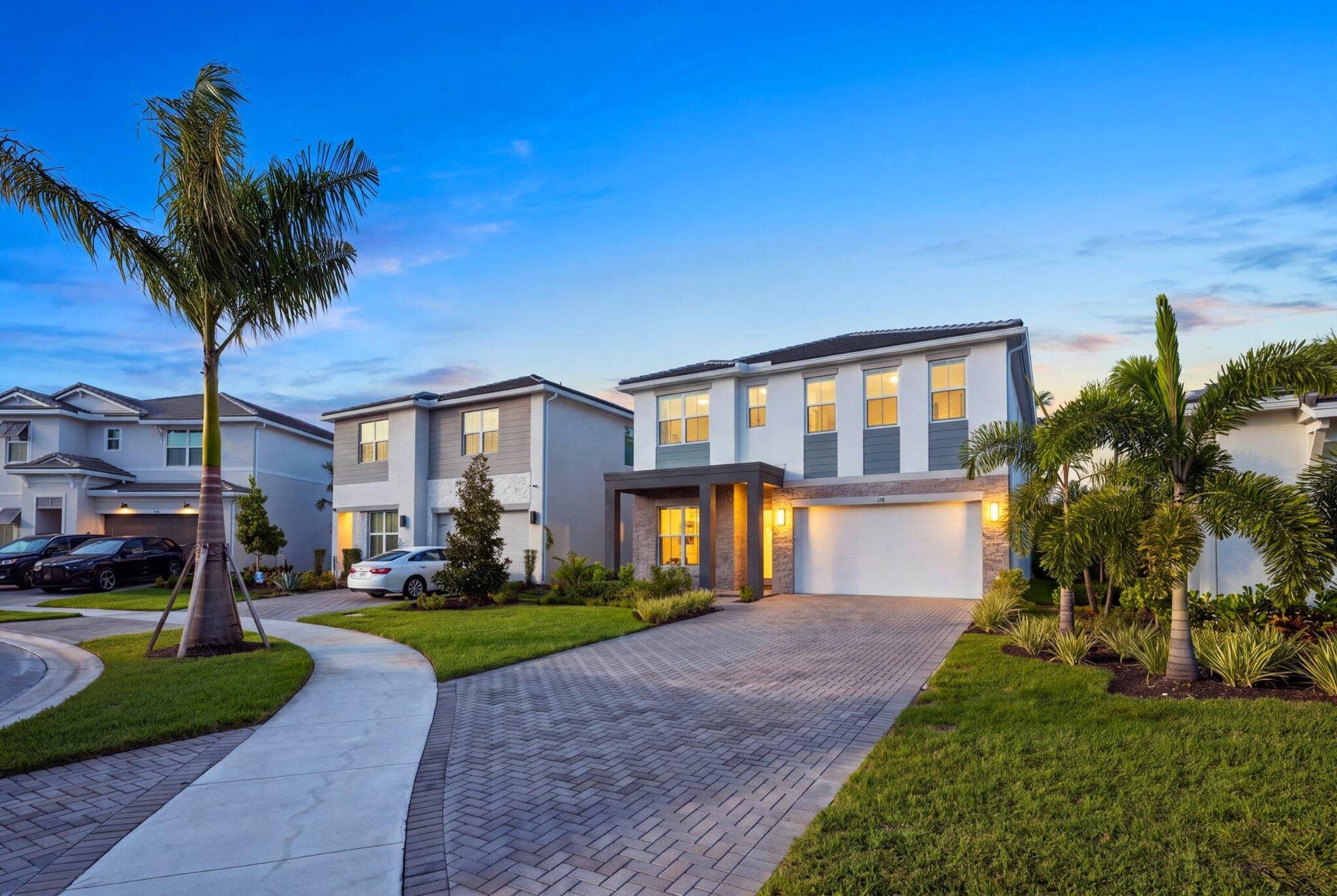 Two-story residence featuring a stone-accented facade, covered entryway, attached two-car garage, and a herringbone-patterned paver driveway