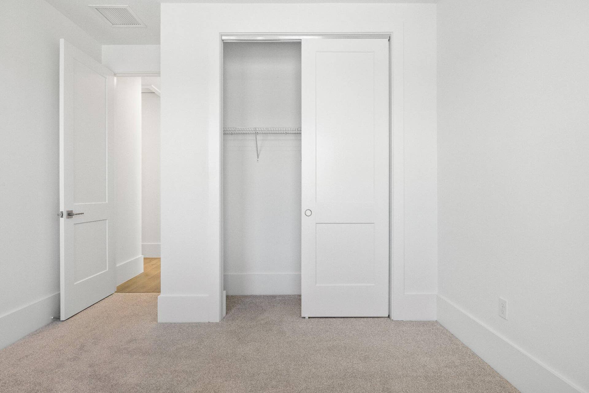 Interior room featuring neutral wall-to-wall carpeting, two-panel interior doors, and a built-in closet with integrated shelving