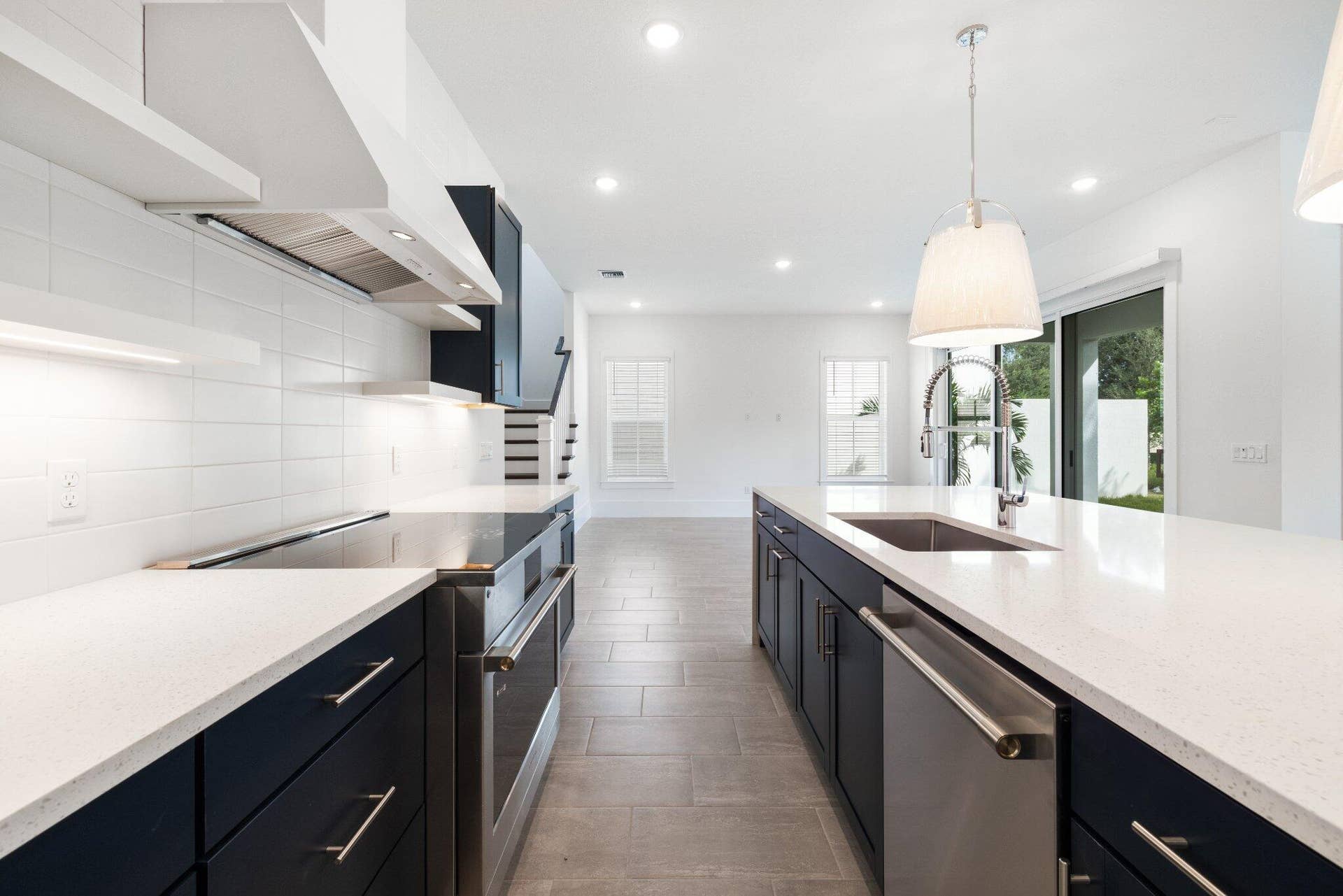 Kitchen featuring dark cabinetry, expansive quartz countertops, stainless steel appliances, white subway tile backsplash, and ceramic tile flooring