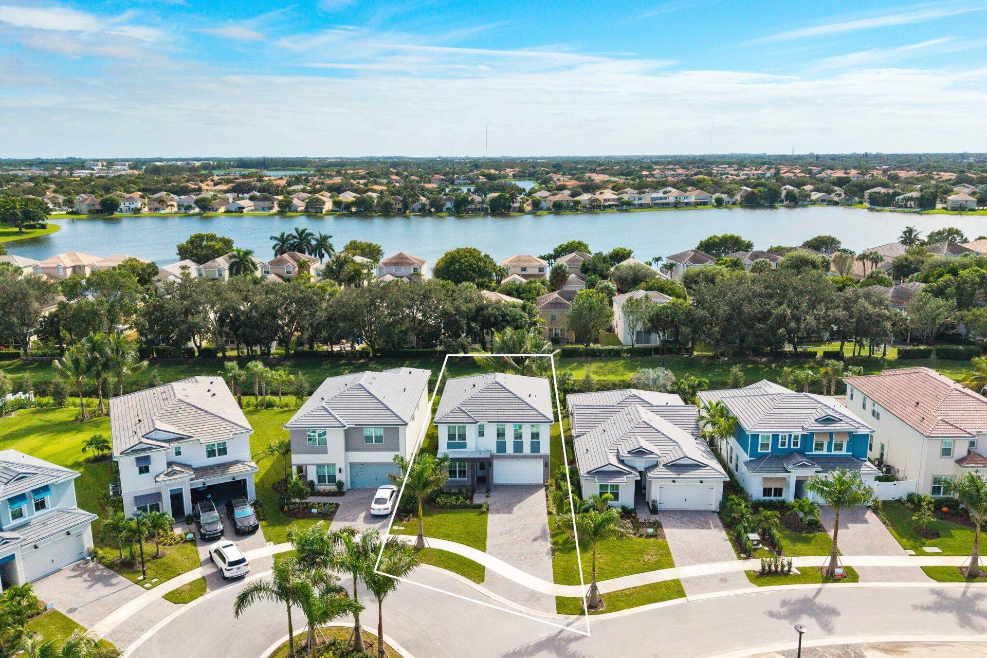 Two-story residence featuring a tile roof, multi-panel windows, paver driveway, and a front-entry garage, positioned on a waterfront lot