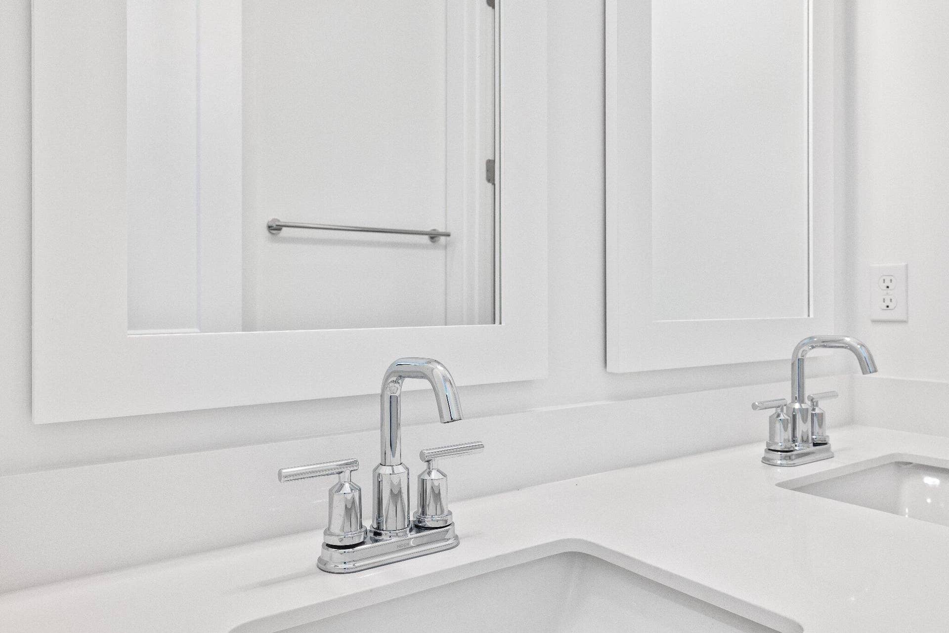 Double vanity featuring white quartz countertops, dual undermount sinks, polished chrome widespread faucets, and matching framed mirrors