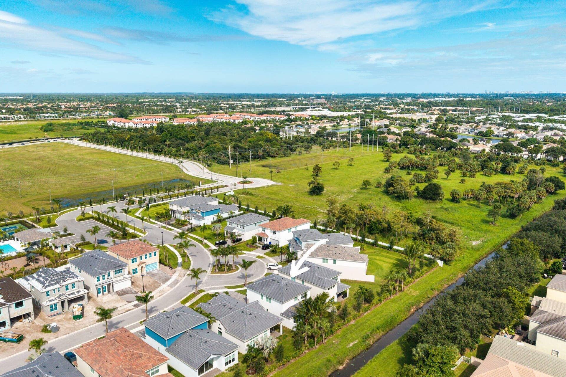 Aerial perspective featuring a two-story residence with a multi-gabled roofline and an attached two-car garage, situated on a perimeter lot bordering open green space
