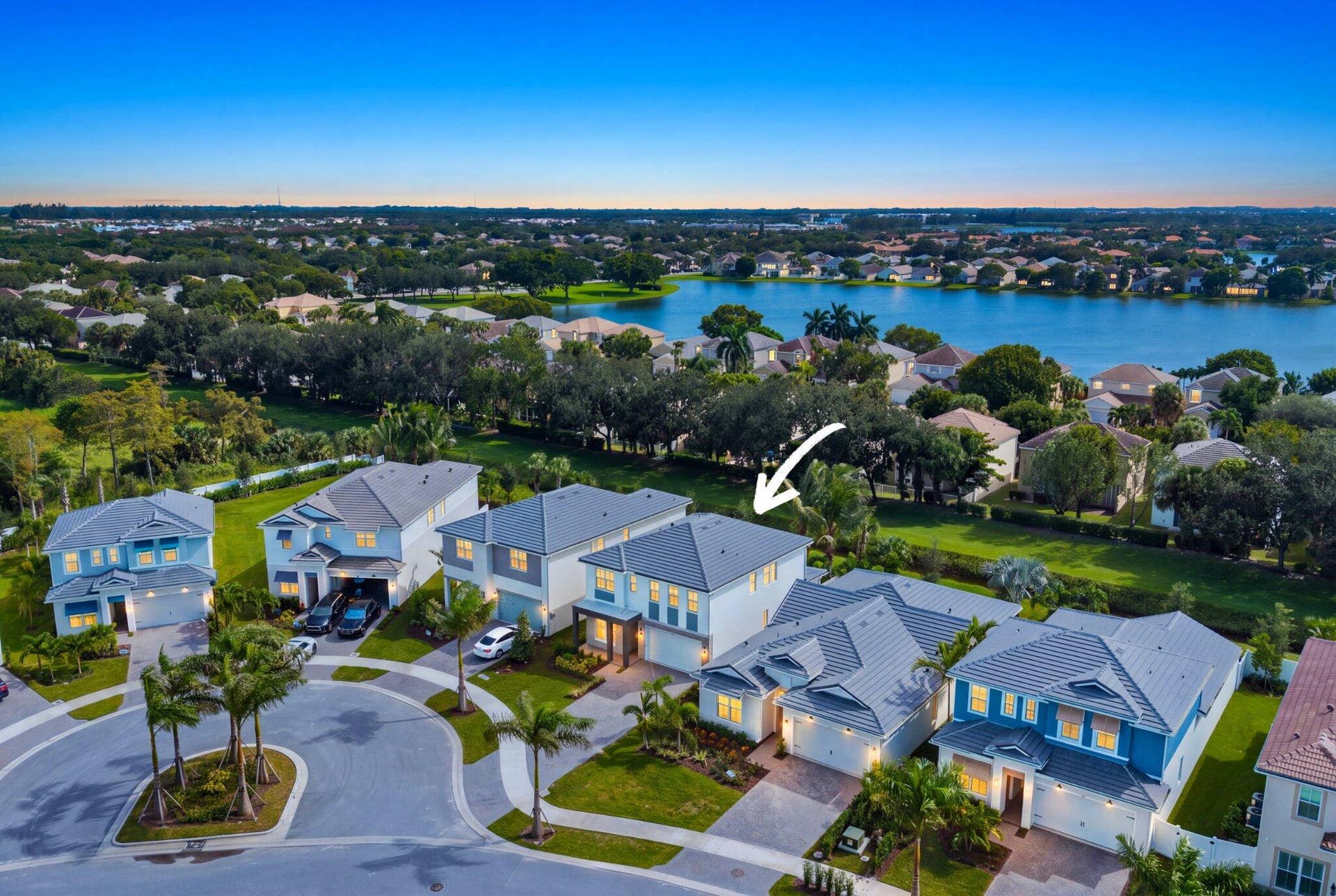 Two-story residence featuring a tile roof, paver driveway, attached two-car garage, and established landscaping