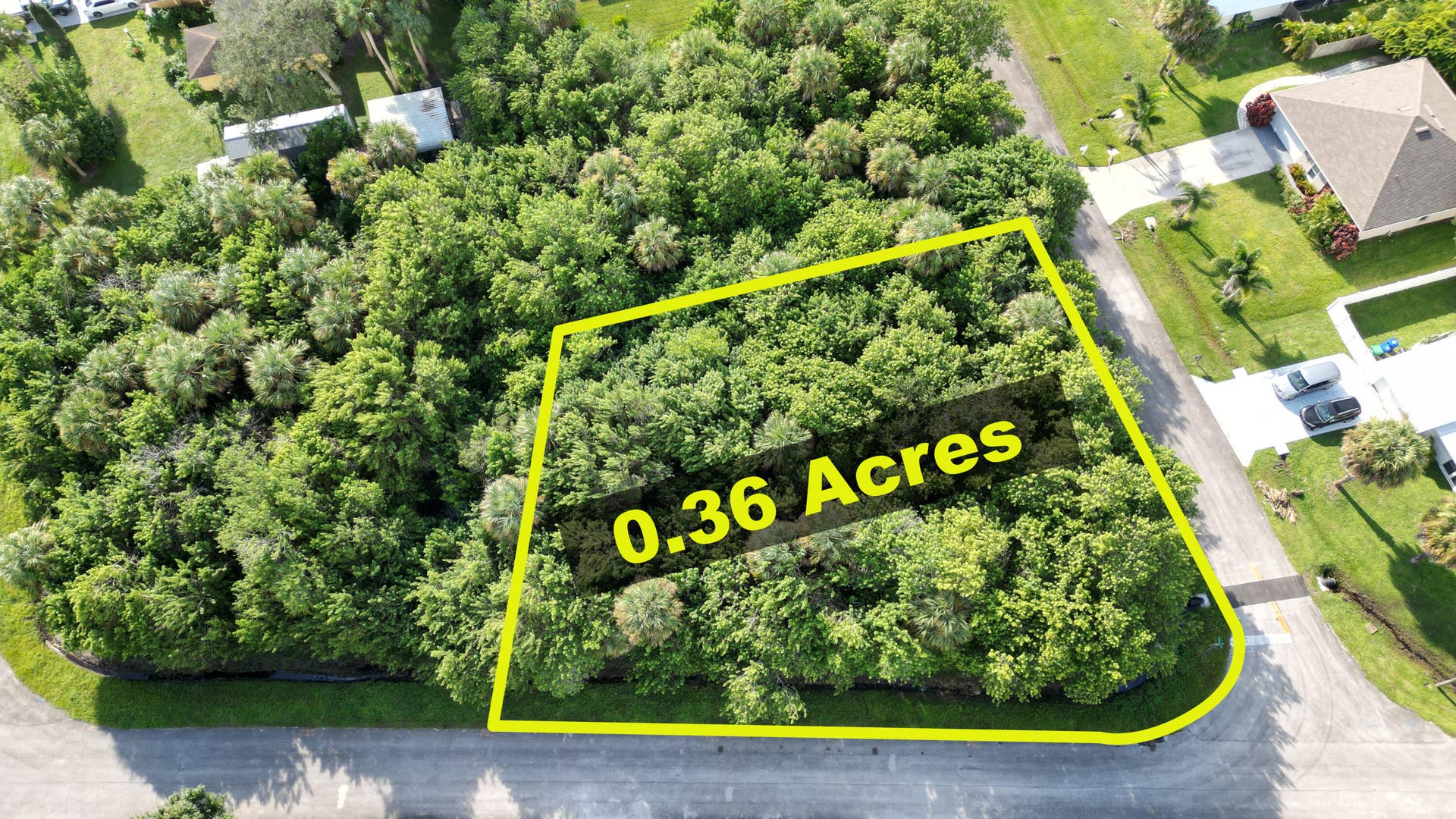 0.36-acre parcel featuring mature native vegetation and trees, situated on a corner lot with frontage on two paved streets