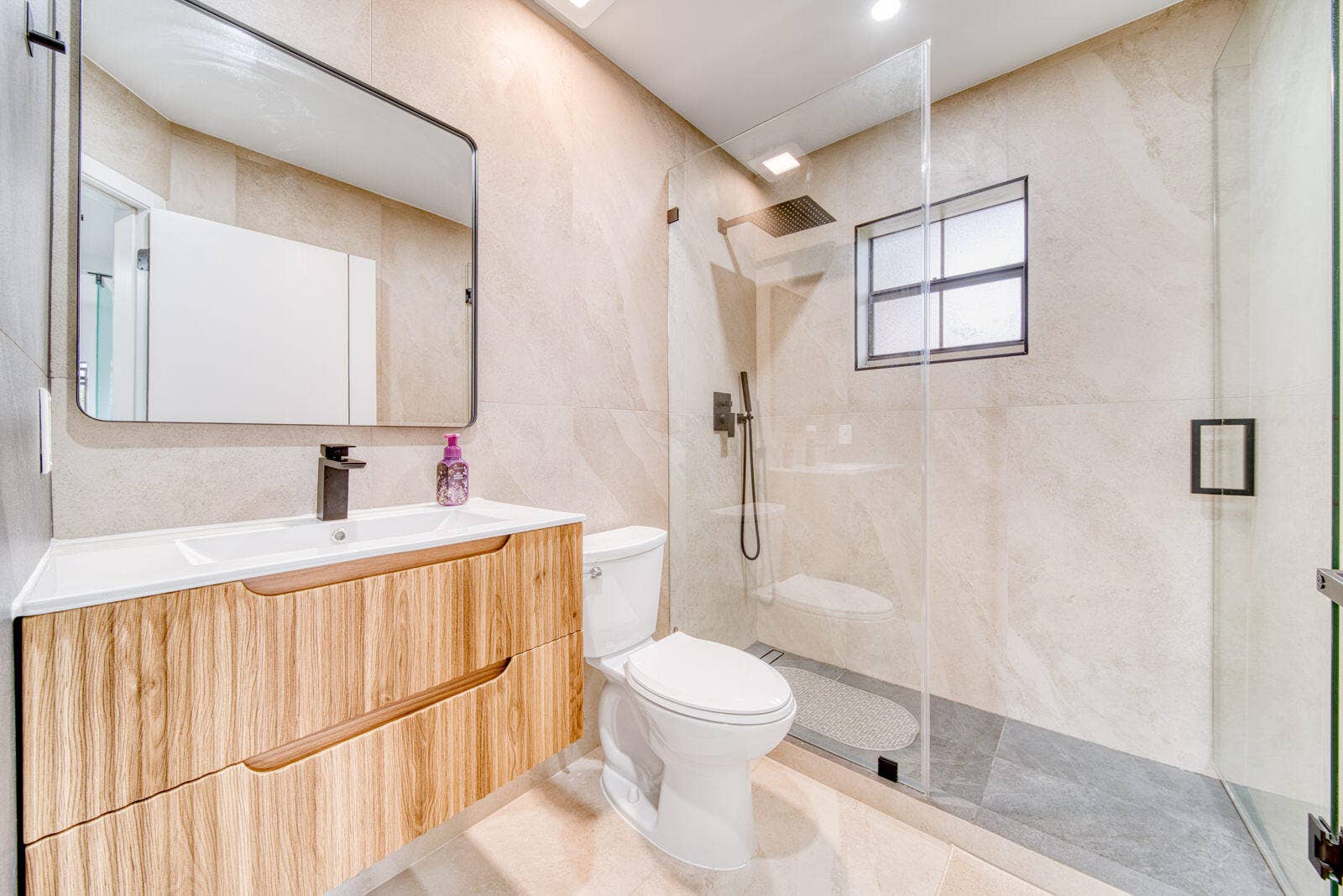 10690 NW 14TH Street, #138, Plantation, FL 33322 Glass-enclosed shower with floor-to-ceiling tile and floating vanity.