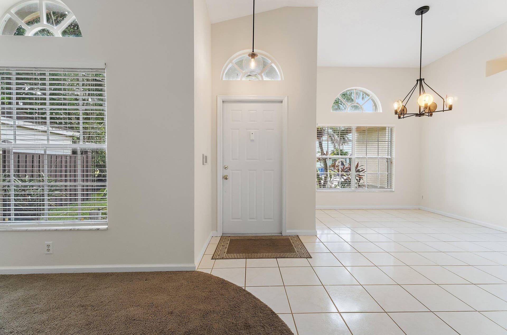6037 Foster Street, Jupiter, FL 33458 Foyer with tile floors, a chandelier and an arched window.