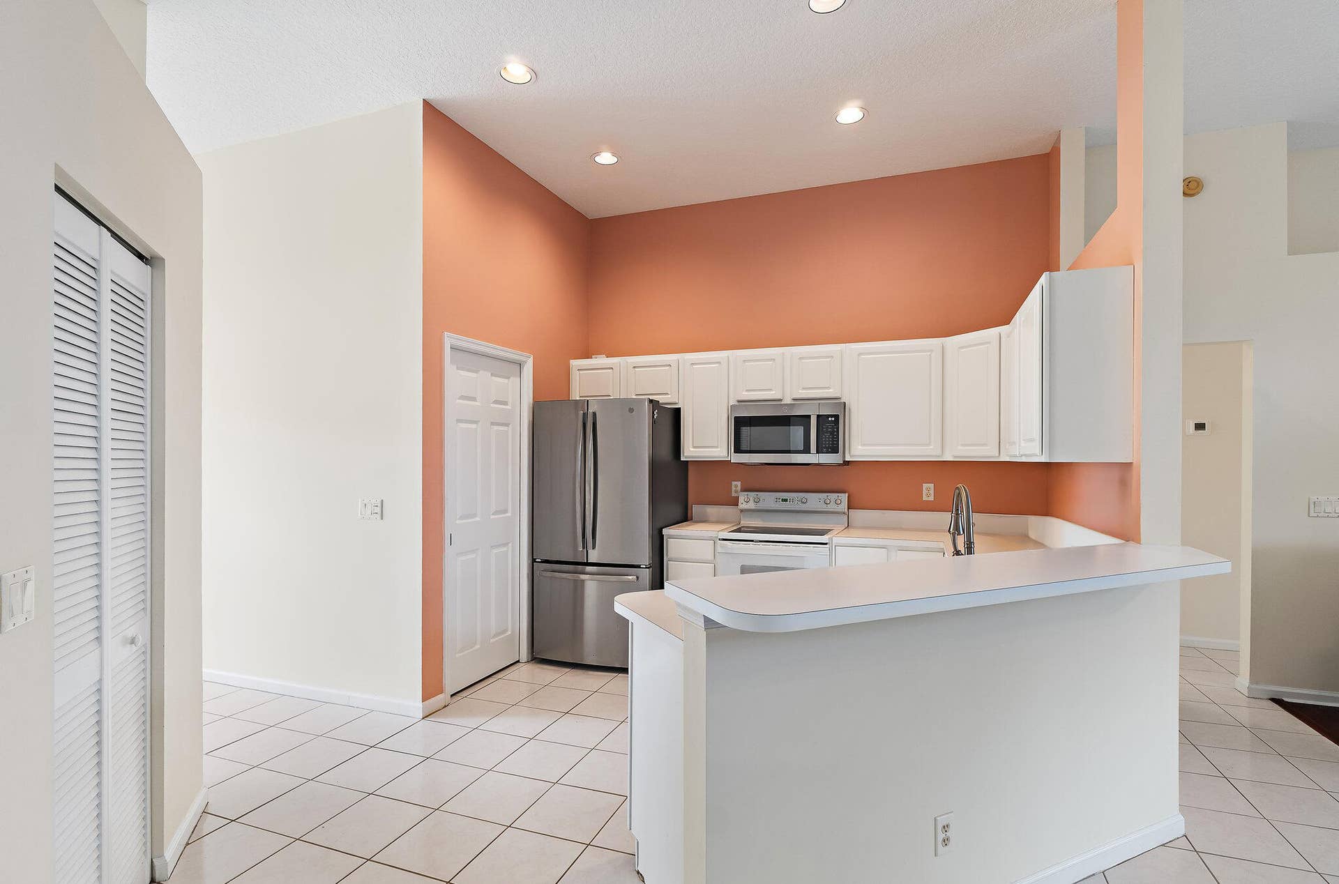 6037 Foster Street, Jupiter, FL 33458 Kitchen with white cabinetry and a stainless refrigerator.
