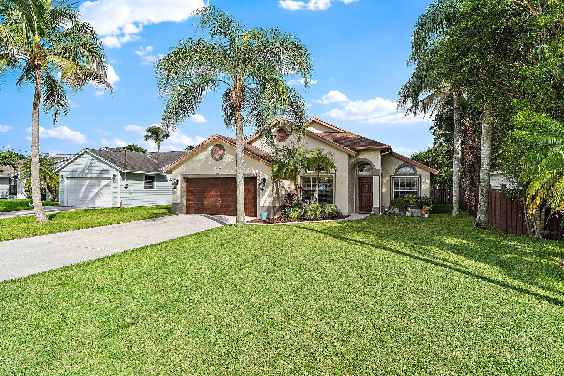 6037 Foster Street, Jupiter, FL 33458 Front yard and driveway with mature palms.