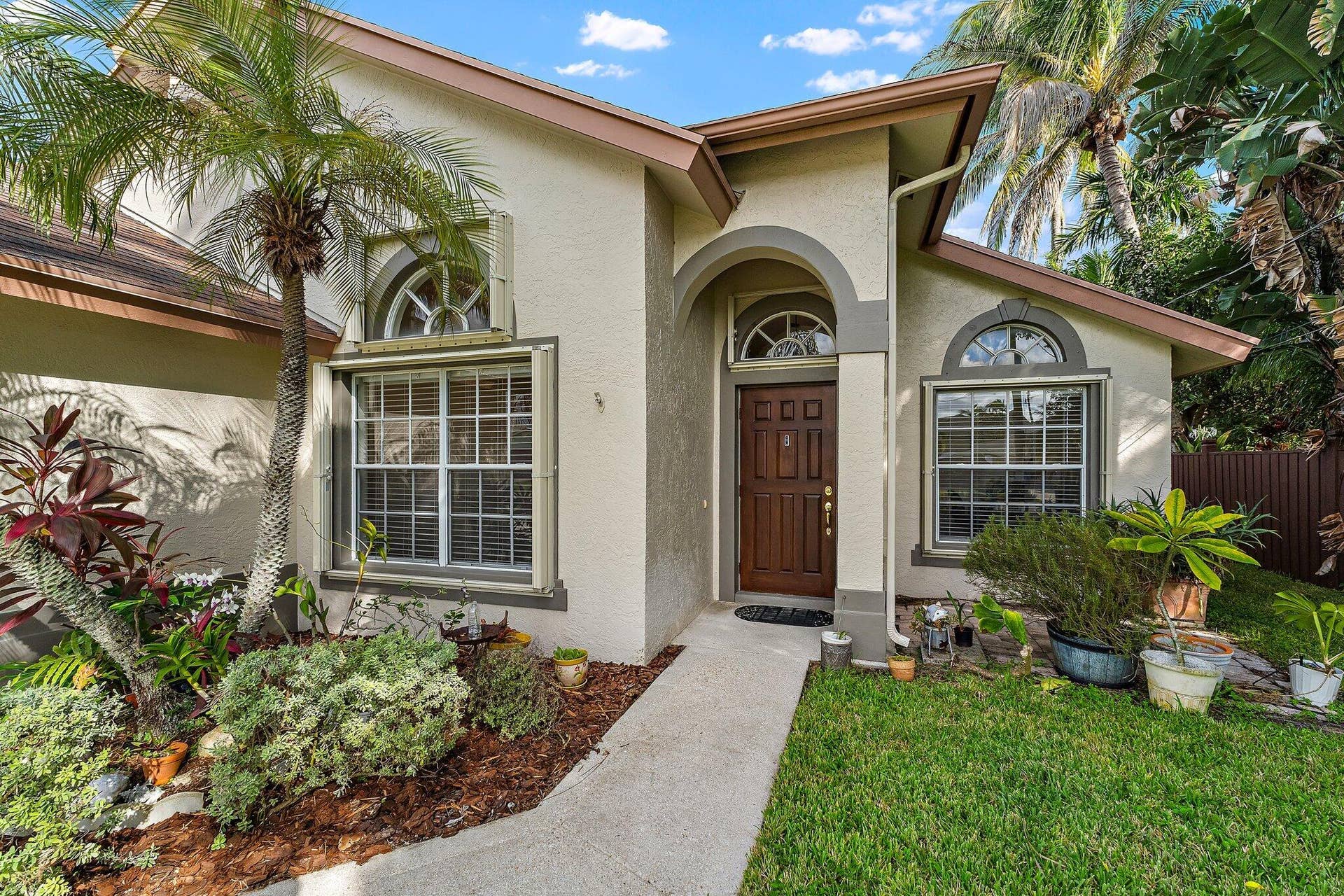 6037 Foster Street, Jupiter, FL 33458 Front entry with arched windows and tropical landscaping.