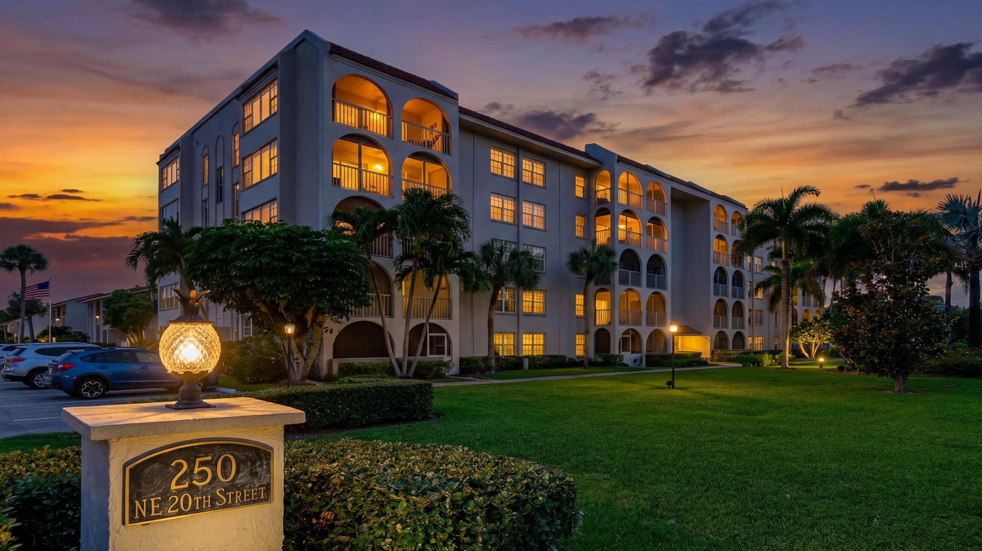250 NE 20TH Street, #5260, Boca Raton, FL 33431 Multi-story residential building featuring arched private balconies, stucco exterior finish, mature palm trees, and manicured grounds