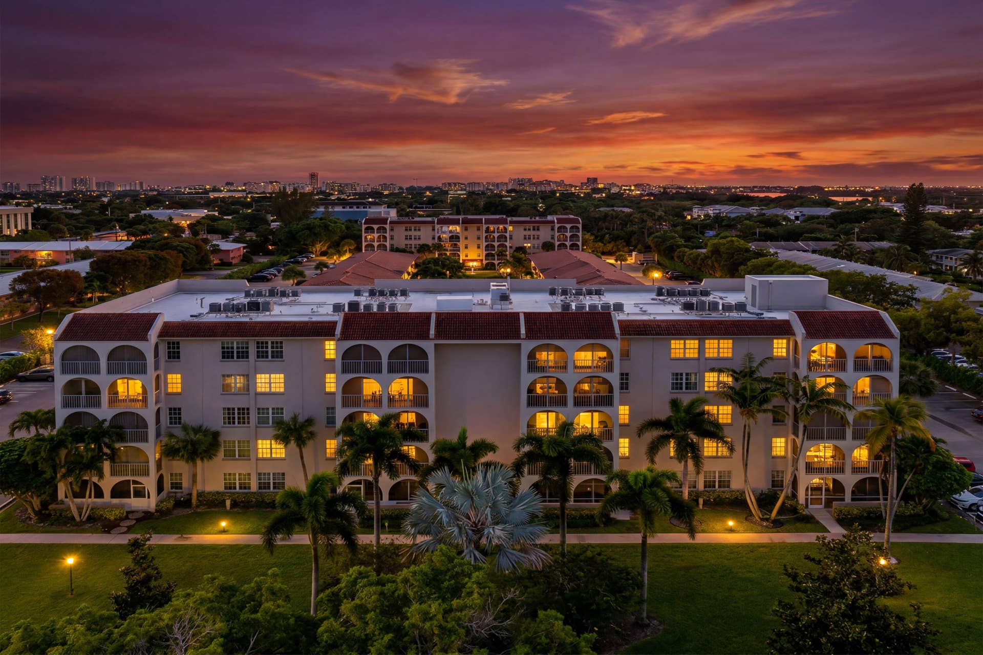 250 NE 20TH Street, #5260, Boca Raton, FL 33431 Multi-story residential building featuring arched balcony enclosures, a decorative tile roof, and manicured landscaping with mature palm trees